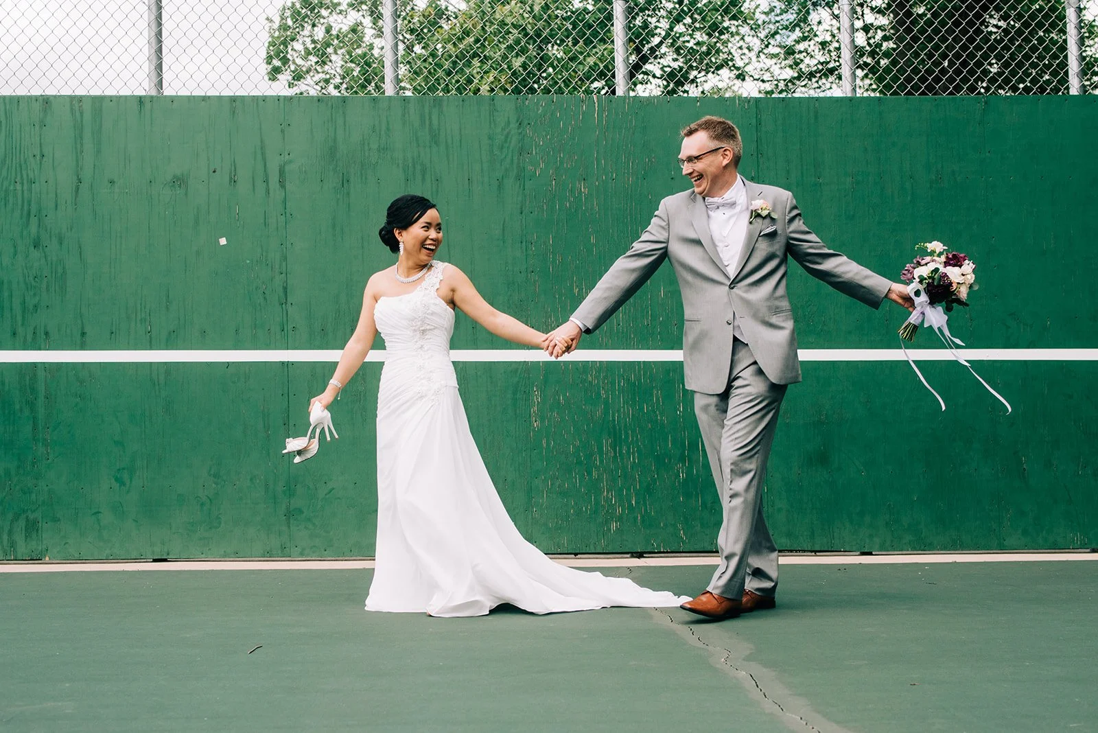 Playful image capturing Bride and Grooms joy while in a tennis court Twin Birch Studio