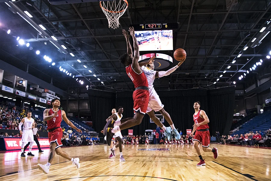Myles Charvis (#7) of the Ryerson Rams goes up for a lay up against Brock Badgers guard Johneil Simpson (#11).