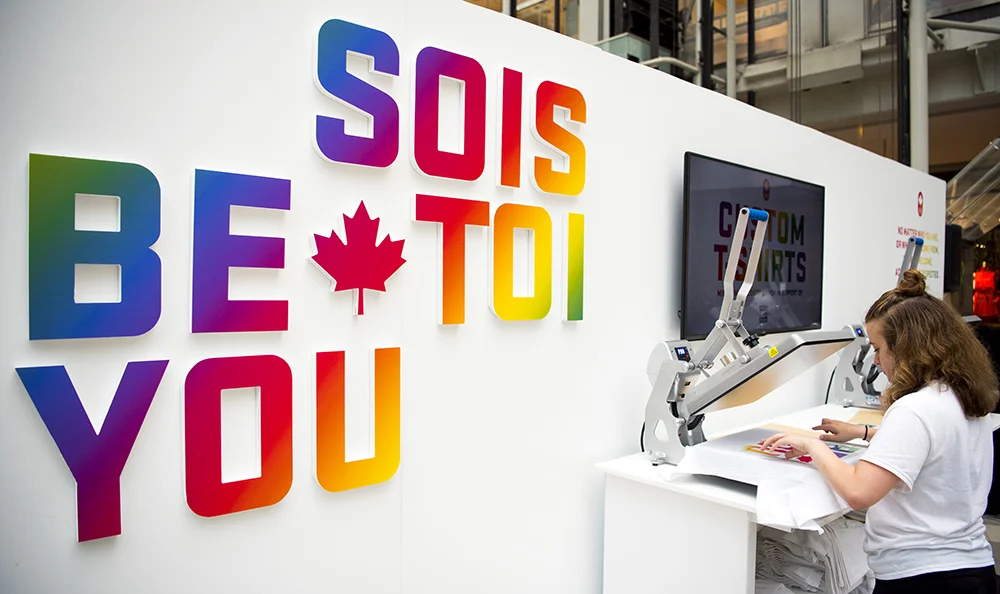 A staff member creates a custom t-shirt at Team Canada’s “Be You“ pop-up shop during Pride Toronto.