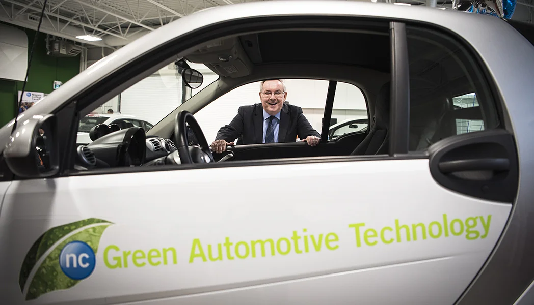 St. Catharines MPP Jim Bradley stands alongside one of the vehicles on display at Niagara College’s Green Automotive Technology Lab during its grand opening.