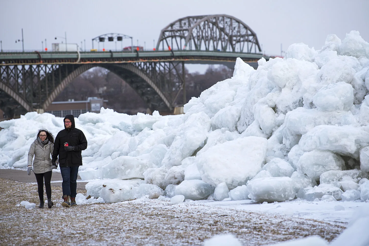 A couple walks alongside a large build up of ice at the shore of Mather Park in Fort Erie, Ont.