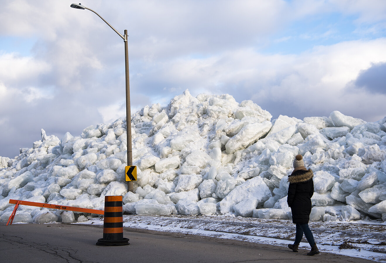 A woman walks alongside a large build up of ice that pushed its way over the Niagara River’s retaining wall in Fort Erie, Ont..