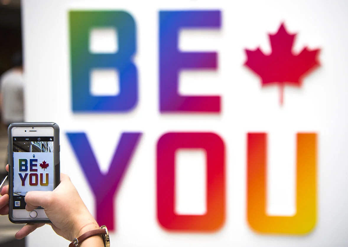 A staff member takes a photo of the “Be You” sign at Team Canada’s pop up store.
