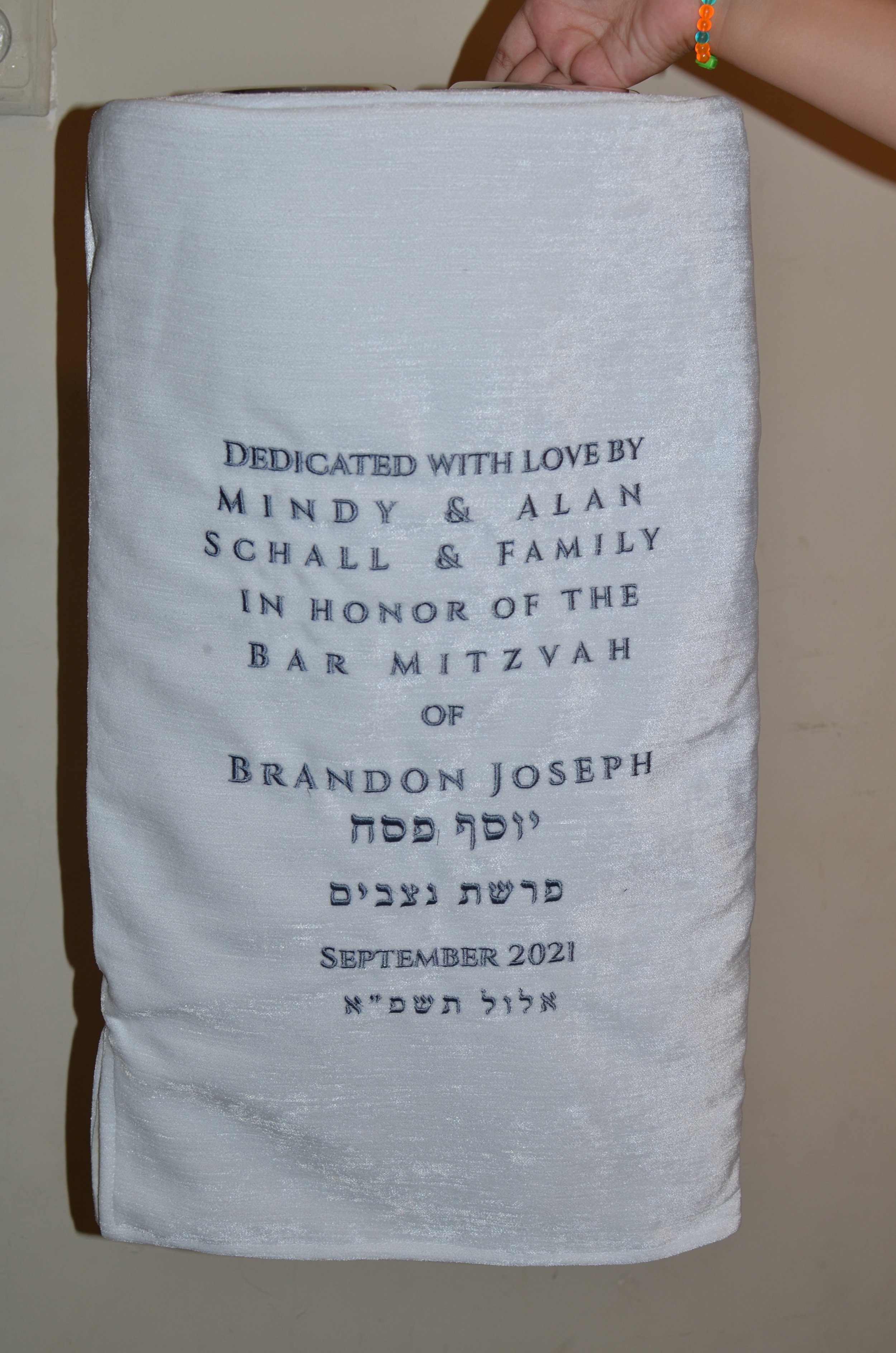  Chana Gamliel's dedication on the Torah Mantel embodies a deep sense of reverence and gratitude. Crafted with meticulous attention to detail, the inscription exudes elegance and spirituality. Each thread is carefully woven into the fabric, reflectin