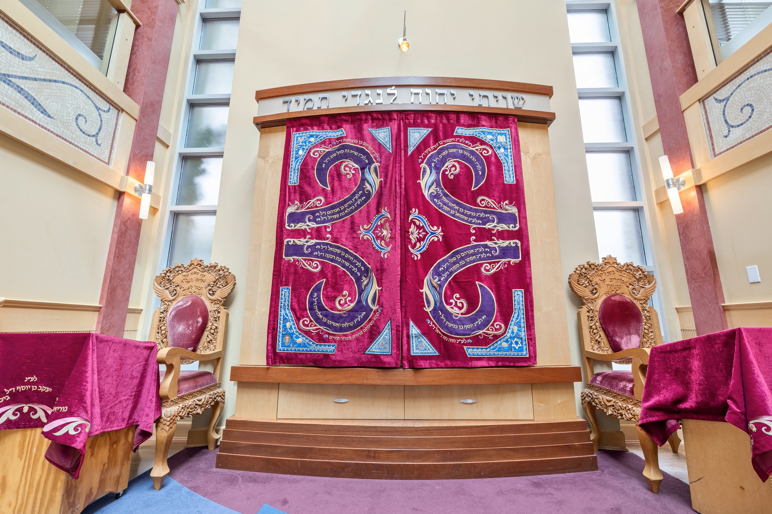   Chana Gamliel's Parochet in Vancouver, Canada, stands as a masterpiece of spiritual artistry. The fabric, carefully selected for its luxurious texture and durability. Within the design, the displaying dedication text, woven with precision, adds a l