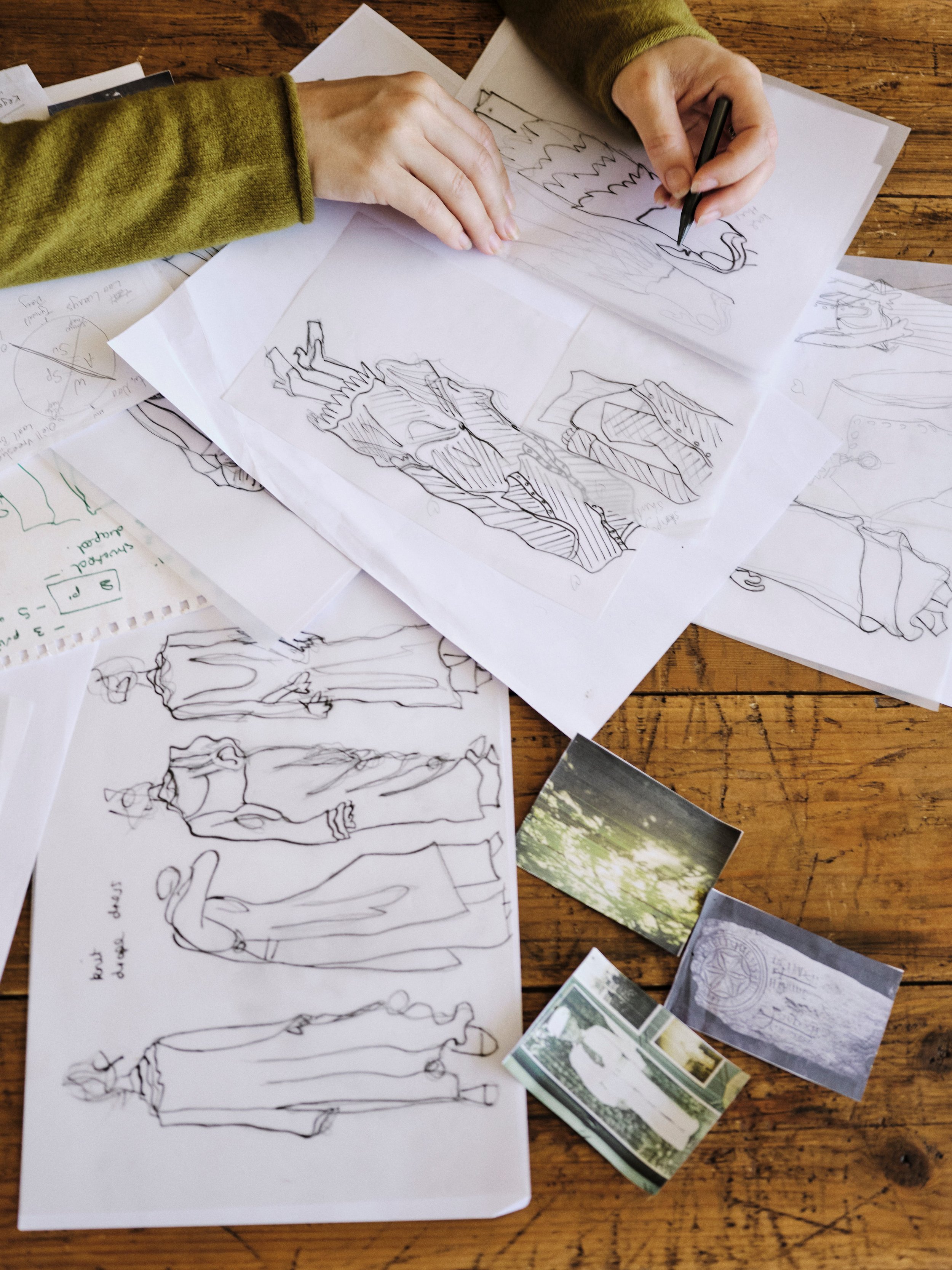 Hands drawing clothing designs on paper