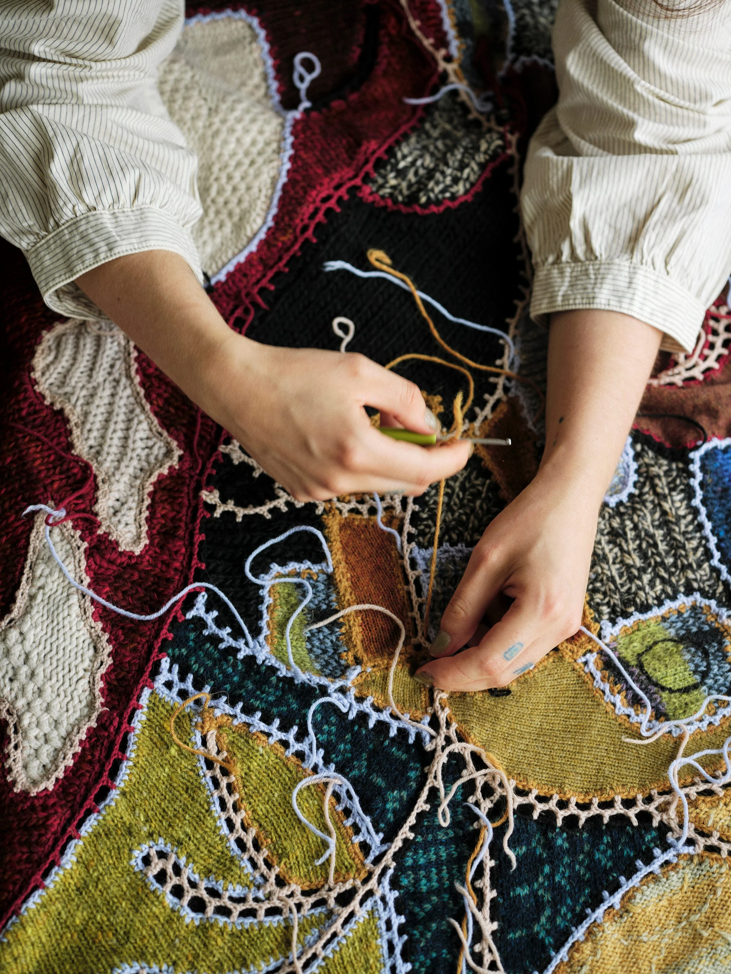 Hands sewing together pieces of knitted fabric