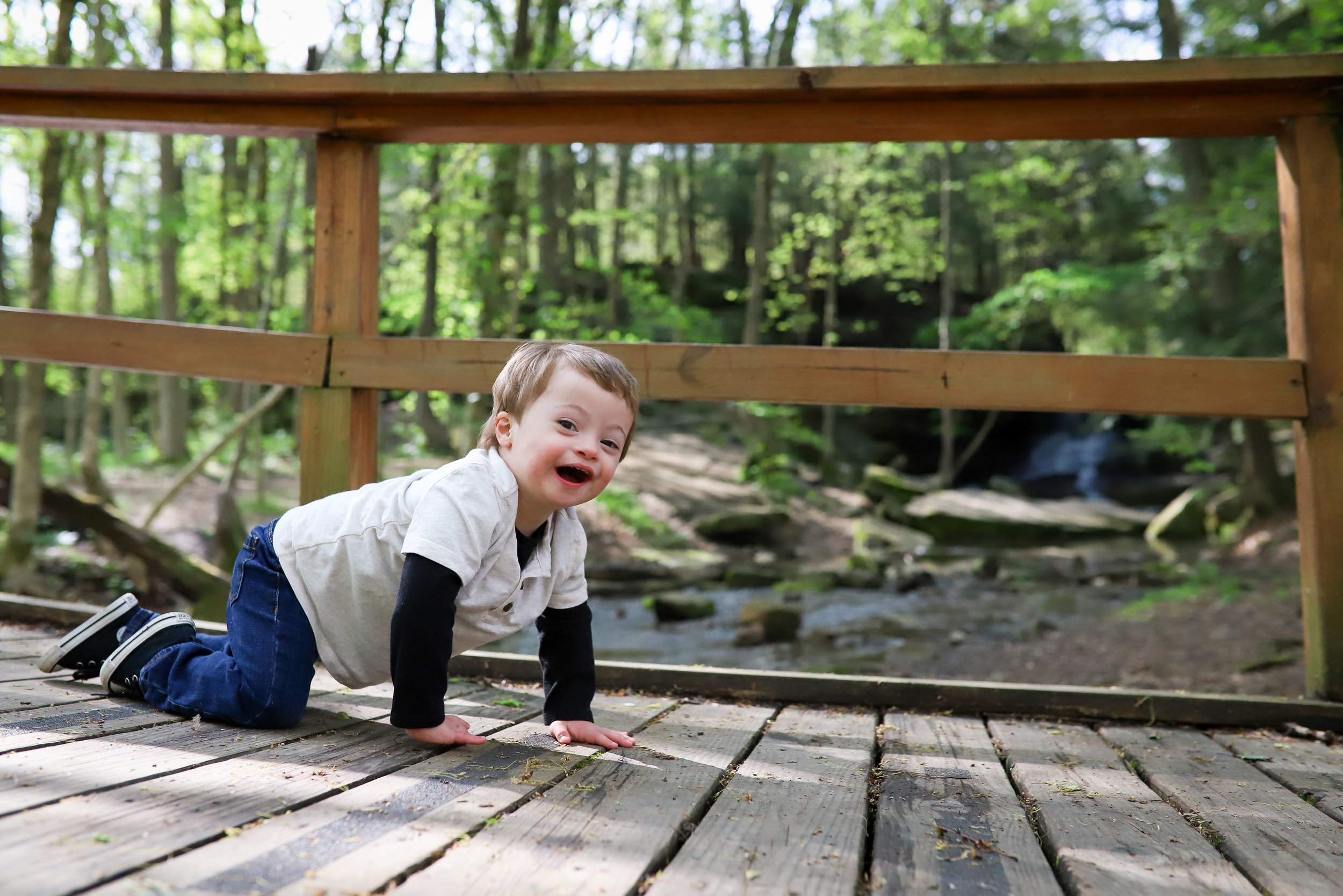 young child with down syndrome crawling on a bridge