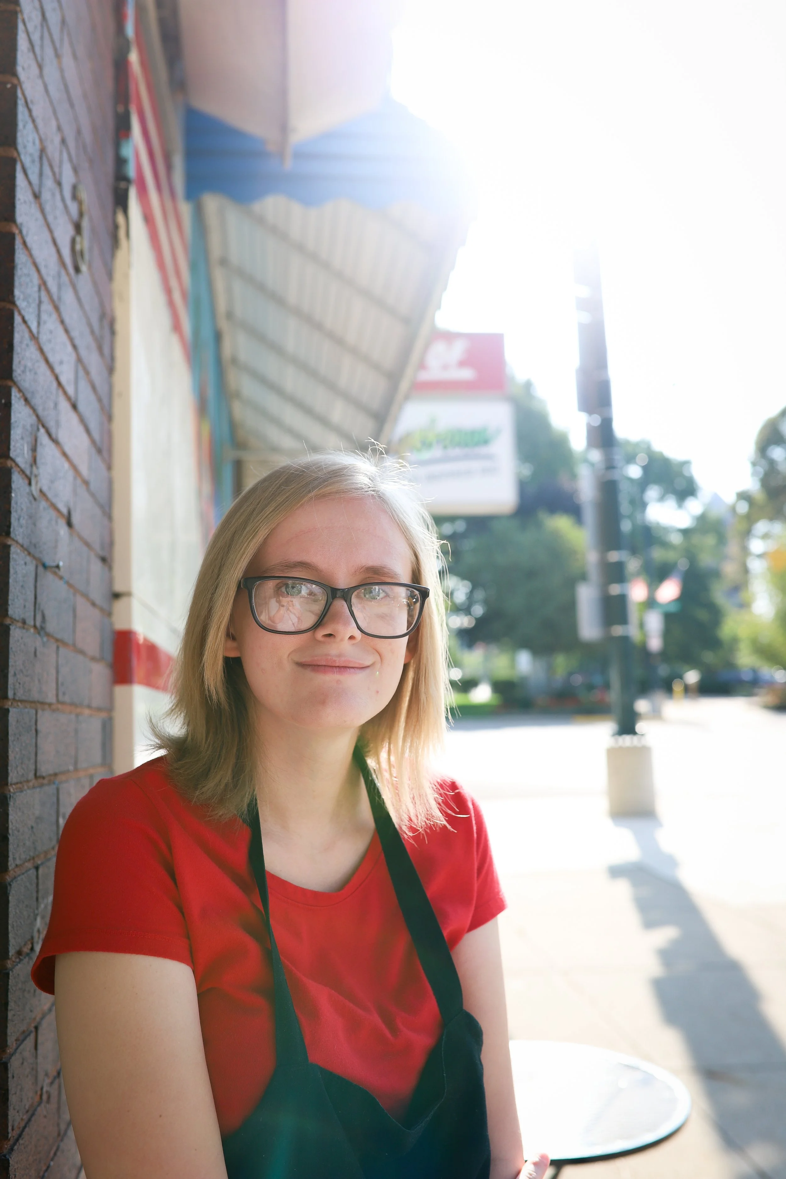 young woman smiling at camera, wearing red shirt