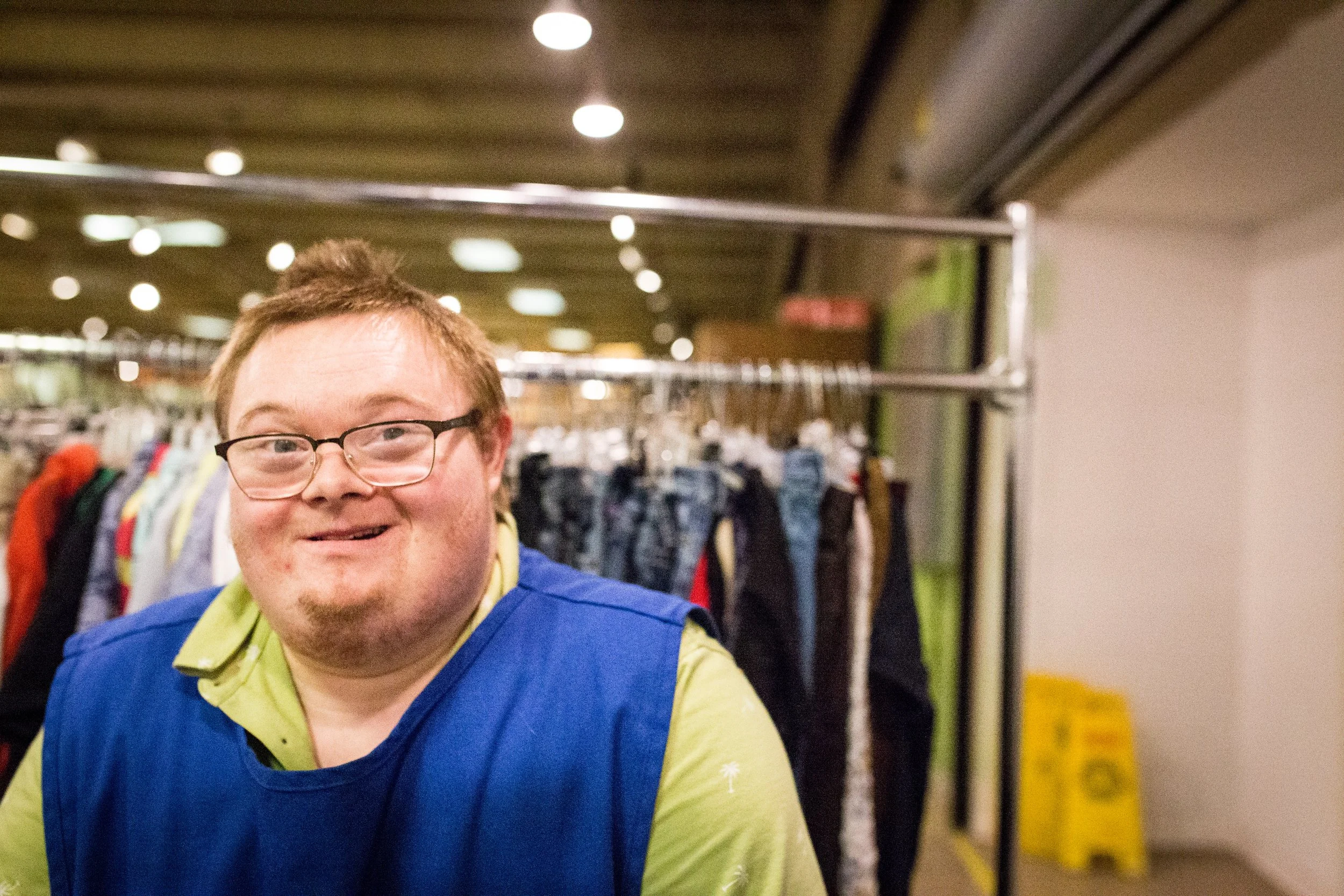 young man with down syndrome smiling at camera while working his job