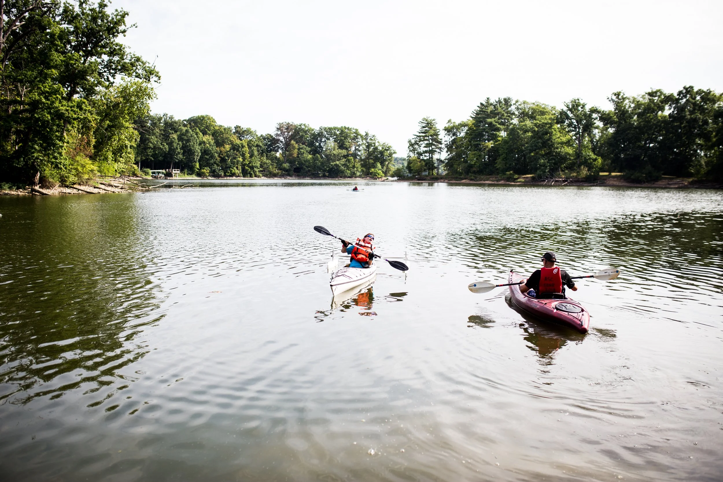 young man with physical disability and his dad each in their own kayak on a river