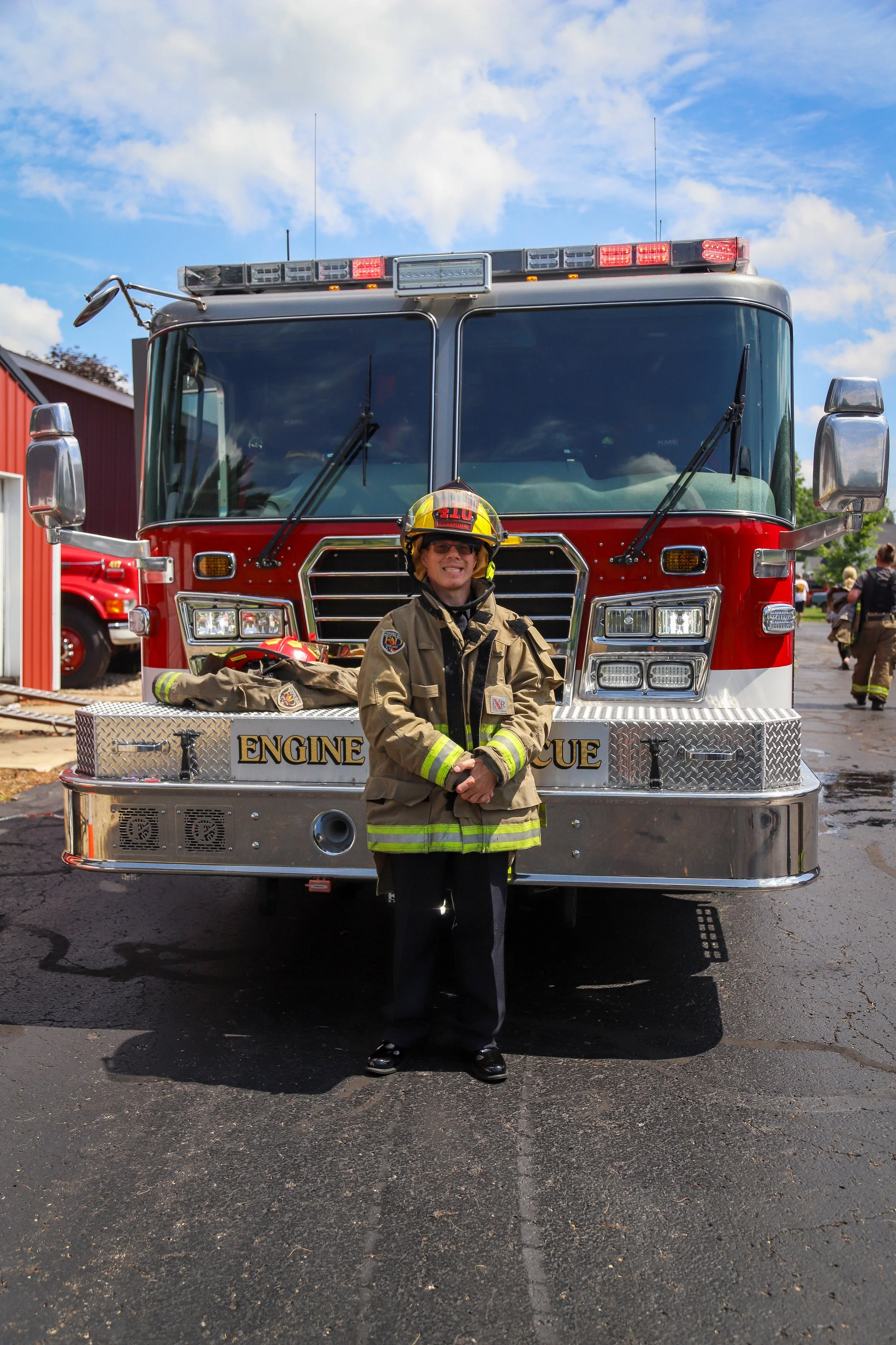 man with disability, honorary fire fighter, standing in front of a fire truck in fireman apparel
