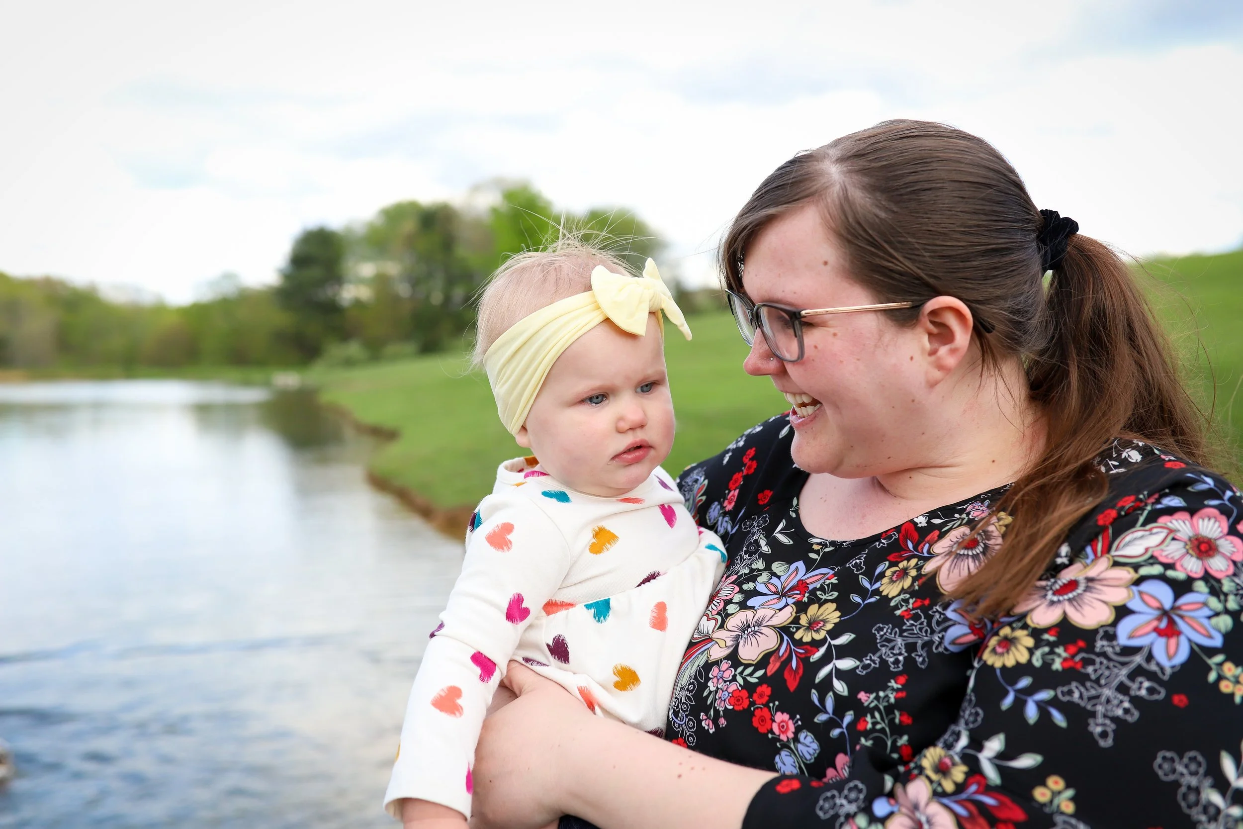 mother smiling at her baby in front of lake