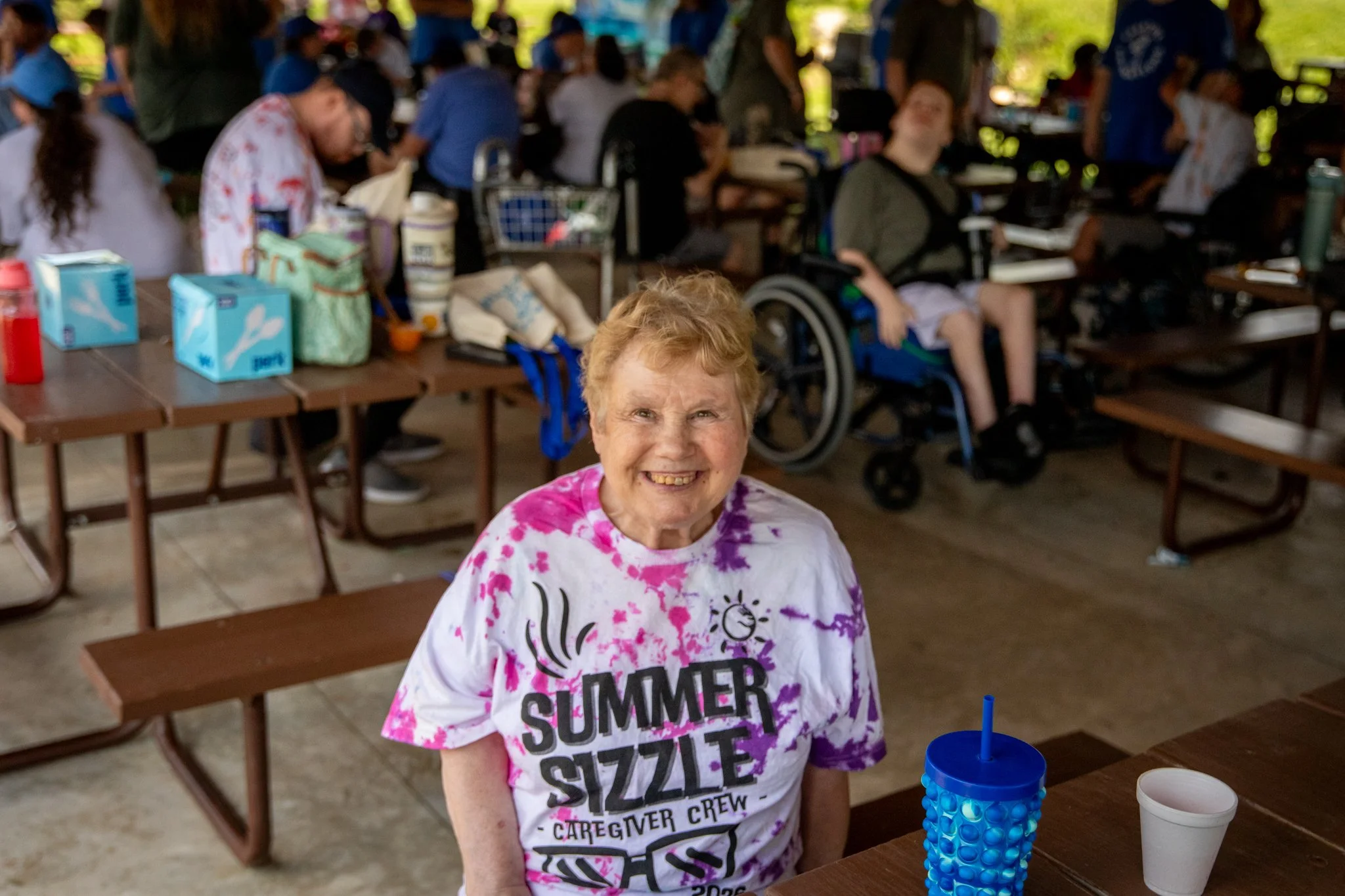 portrait of a woman wearing a tie dye shirt smiling at the camera
