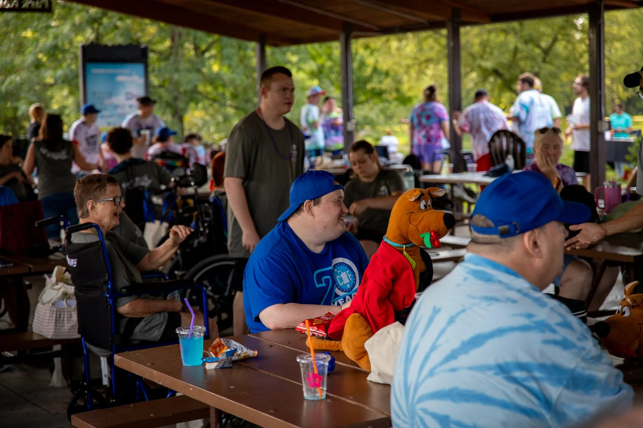 young man wearing blue hat and shirt, smiling and hanging out with a group of friends