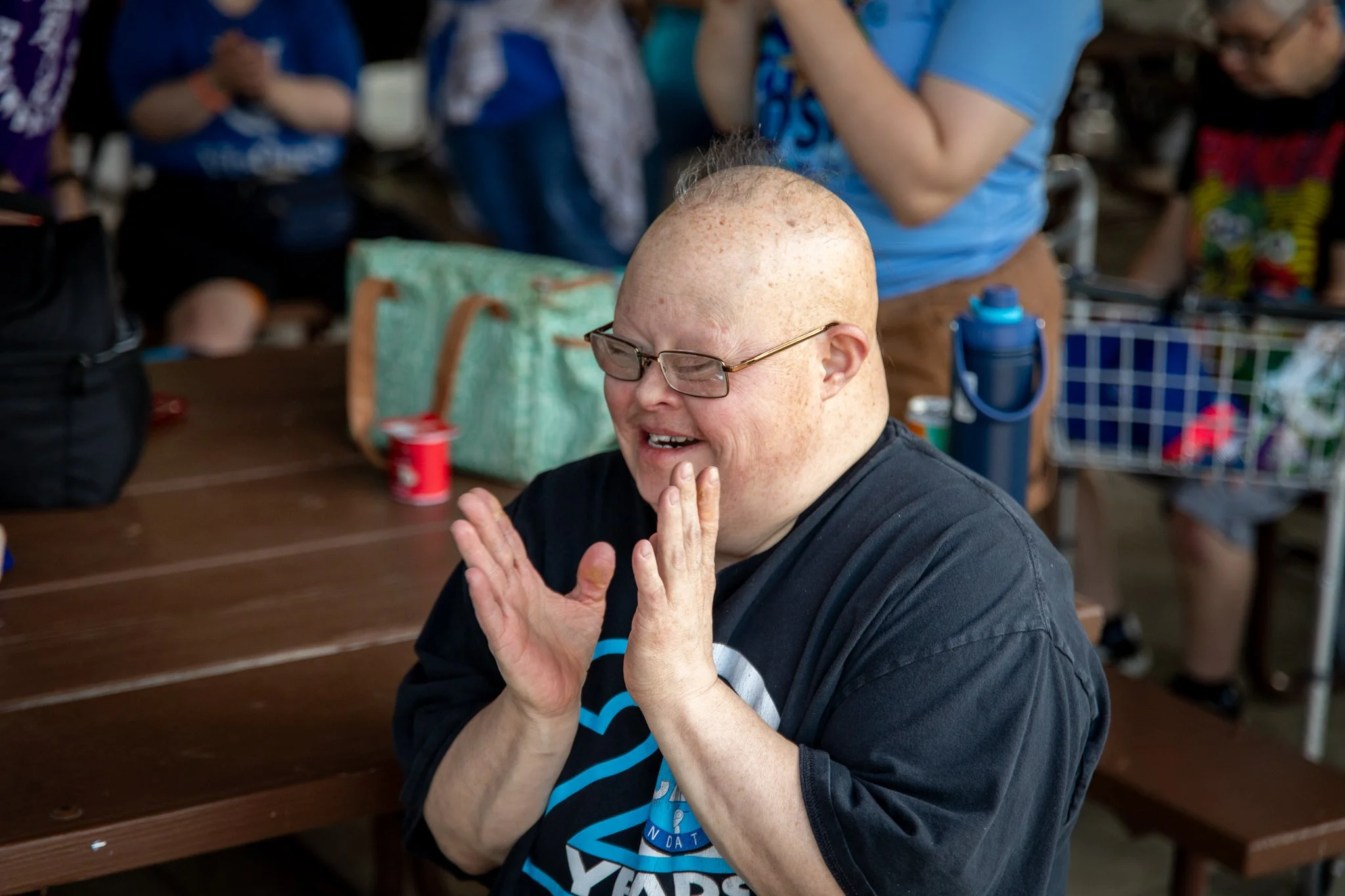 portrait of woman with bald head, smiling and clapping her hands together