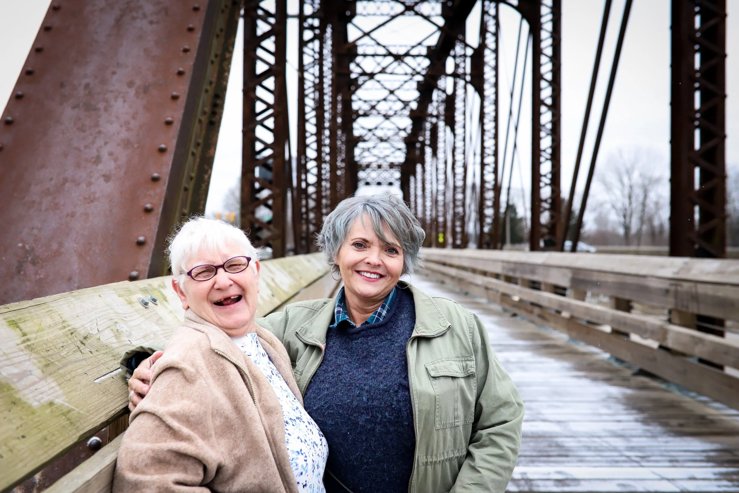 two women standing on a bridge smiling