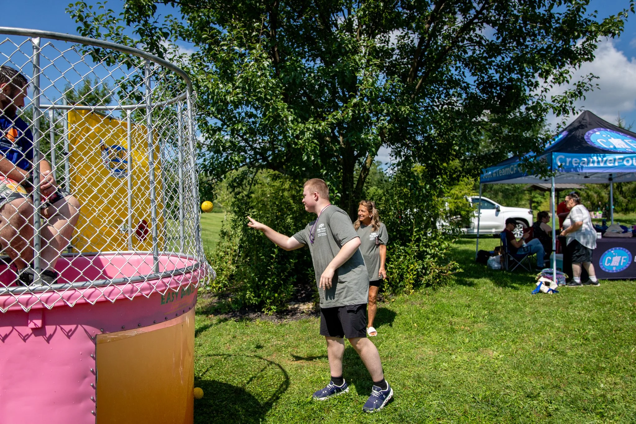 young man throwing a ball at the dunk tank to dunk the police officer