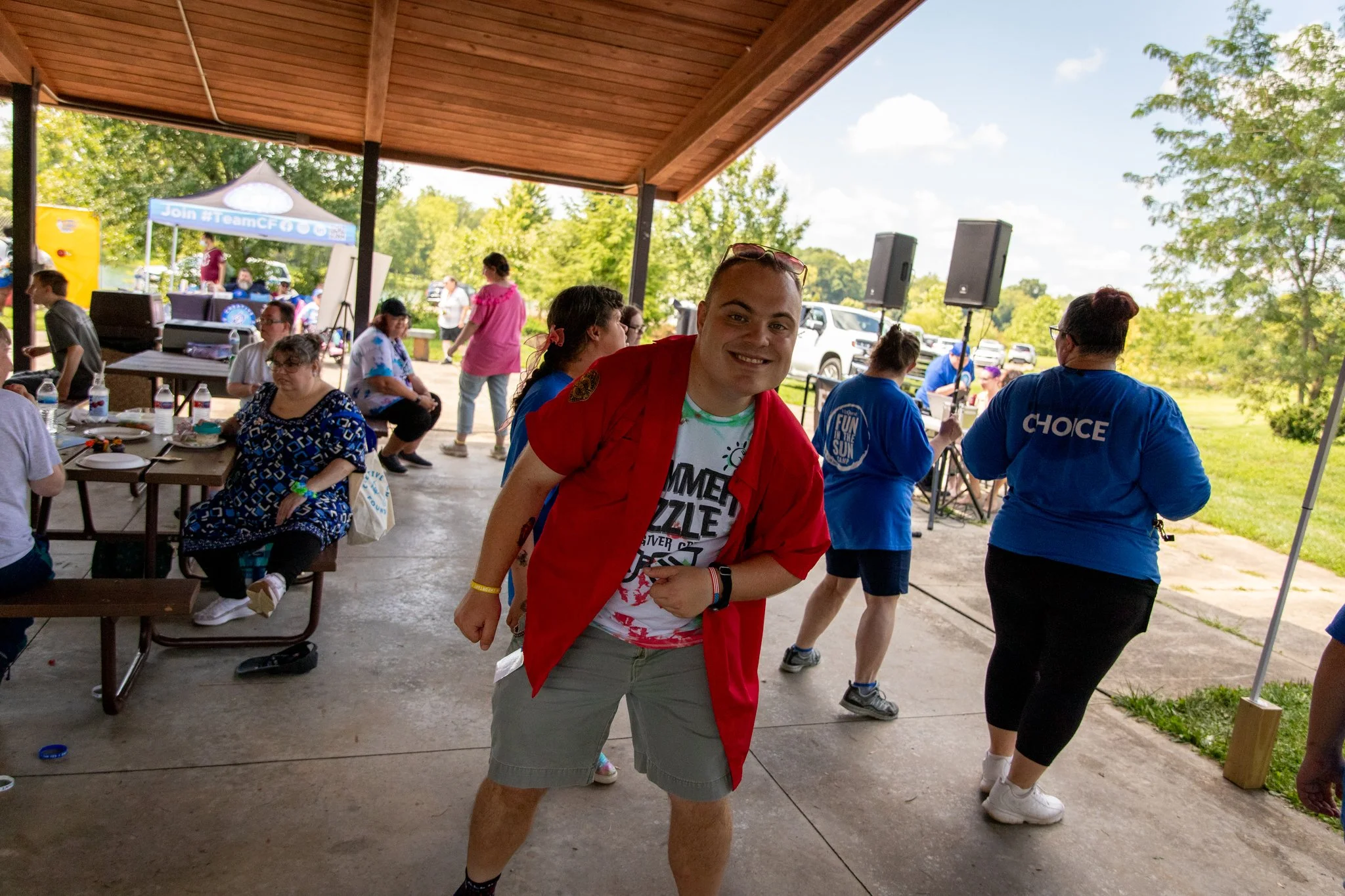 a young man wearing red shirt dancing, other people dancing in the background