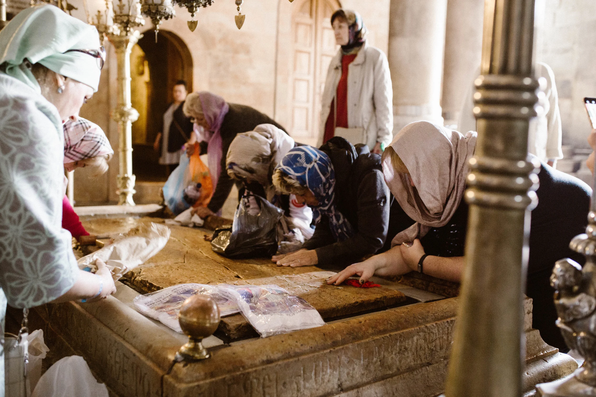 Women praying on the stone where Jesus's body was prepared for burial