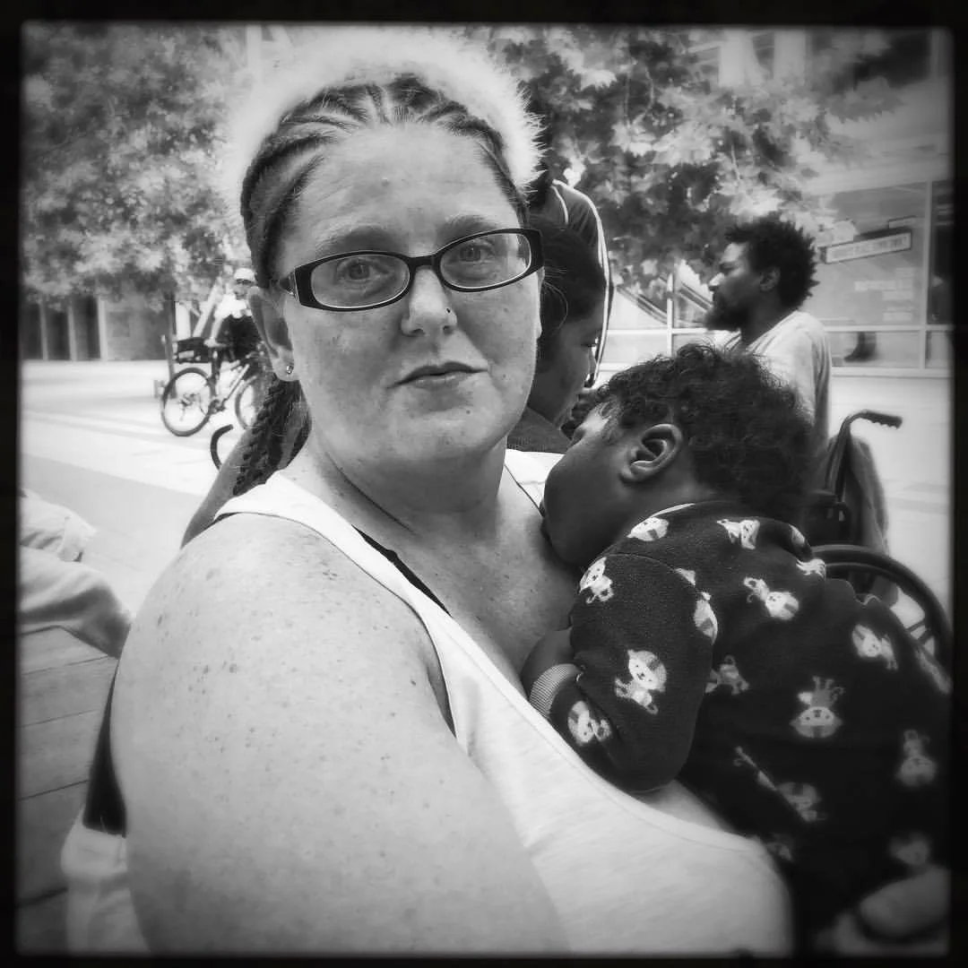 Saptember 1, 2017 This is Amber. She evacuated to the #houstonconvention center after water rapidly rose in her home. As she fled the water she was mugged while seeking refuge, losing what little she had. She wasn't bitter about it, but said she had to keep going, thankful to be alive. The little boy she's holding is Joshua, 3 months old today. Joshua is not her child but the boy of a woman whom she made friends with in the shelter. Wanting to give Joshua's mom a rest, Amber took the child into her own arms, in 102f degree(39C) heat. Such generosity is not uncommon to what I've witnessed the past 3 days, but is tremendously special. #harvey , #hurricaneharvey , #hurricane , #houston , #texas , #climatechange , #climatechangeisreal , #healing