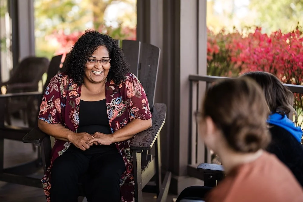 A woman sitting and speaking with two other people