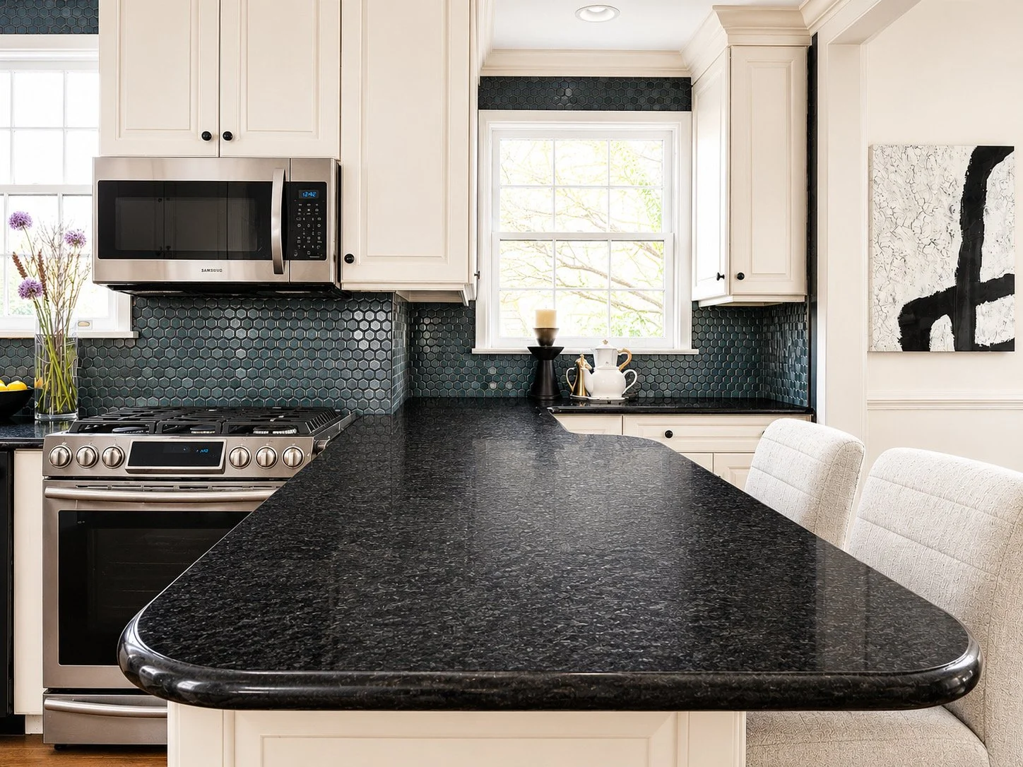 Designer kitchen detail at 5000 Cary Street Road in Richmond, VA featuring black countertops, geometric backsplash tile, stainless steel appliances, and luxury staging.