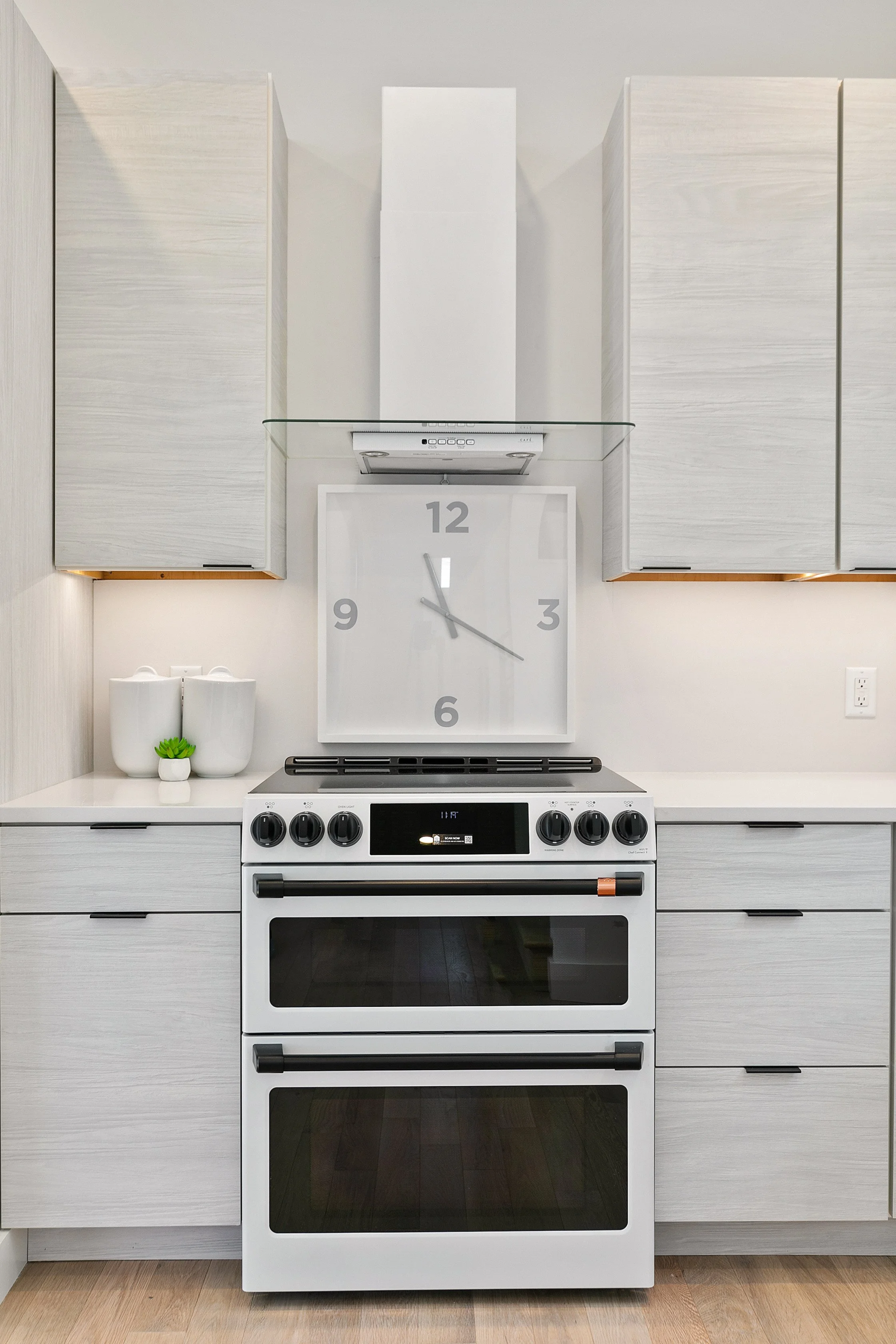 Clean modern kitchen with white range, glass hood, and large clock professionally staged at 2 N Brunswick St Richmond VA