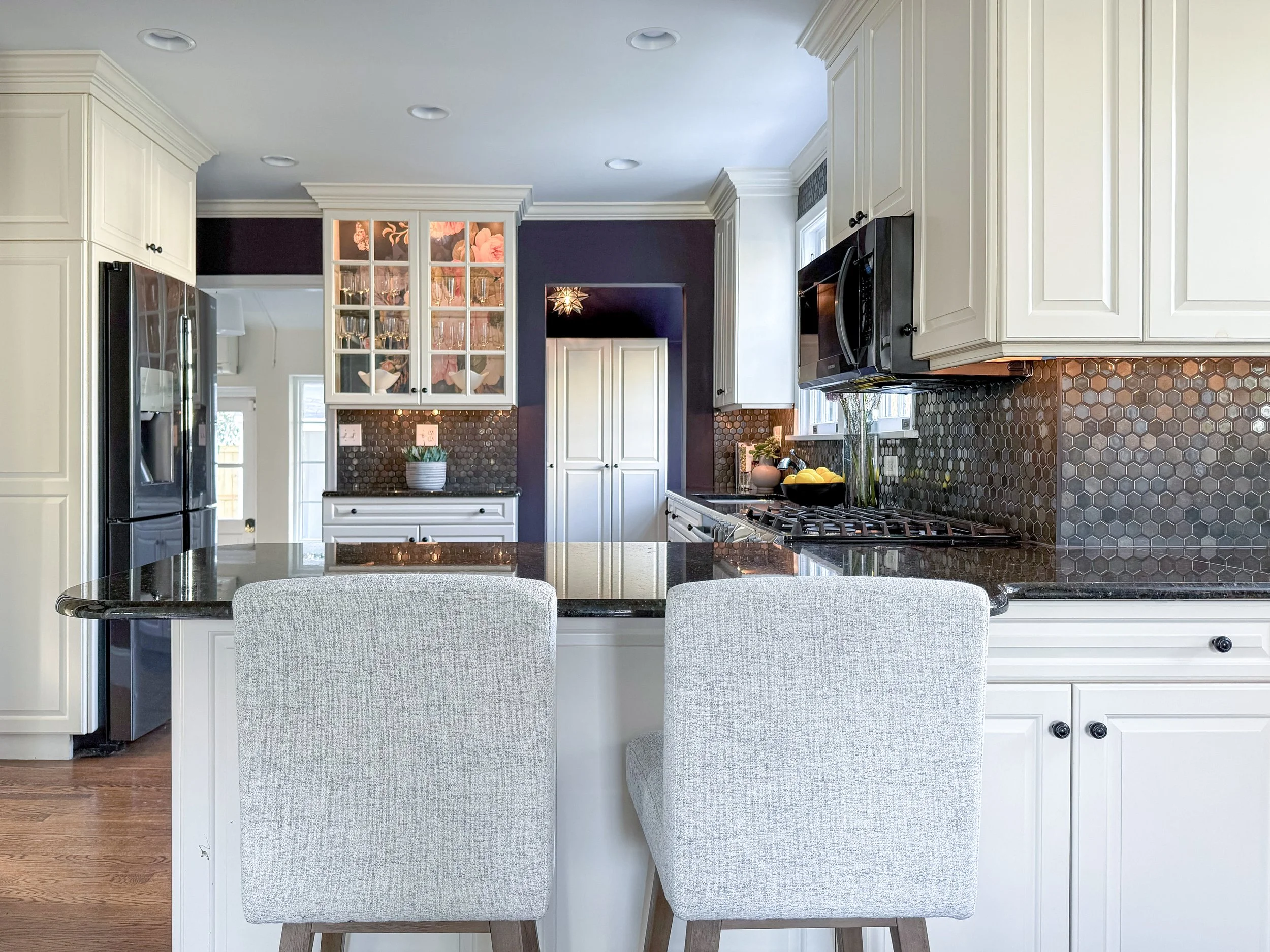 Luxury kitchen at 5000 Cary Street Road in Richmond, VA featuring white custom cabinetry, dark countertops, designer backsplash, black appliances, and professionally staged interiors.