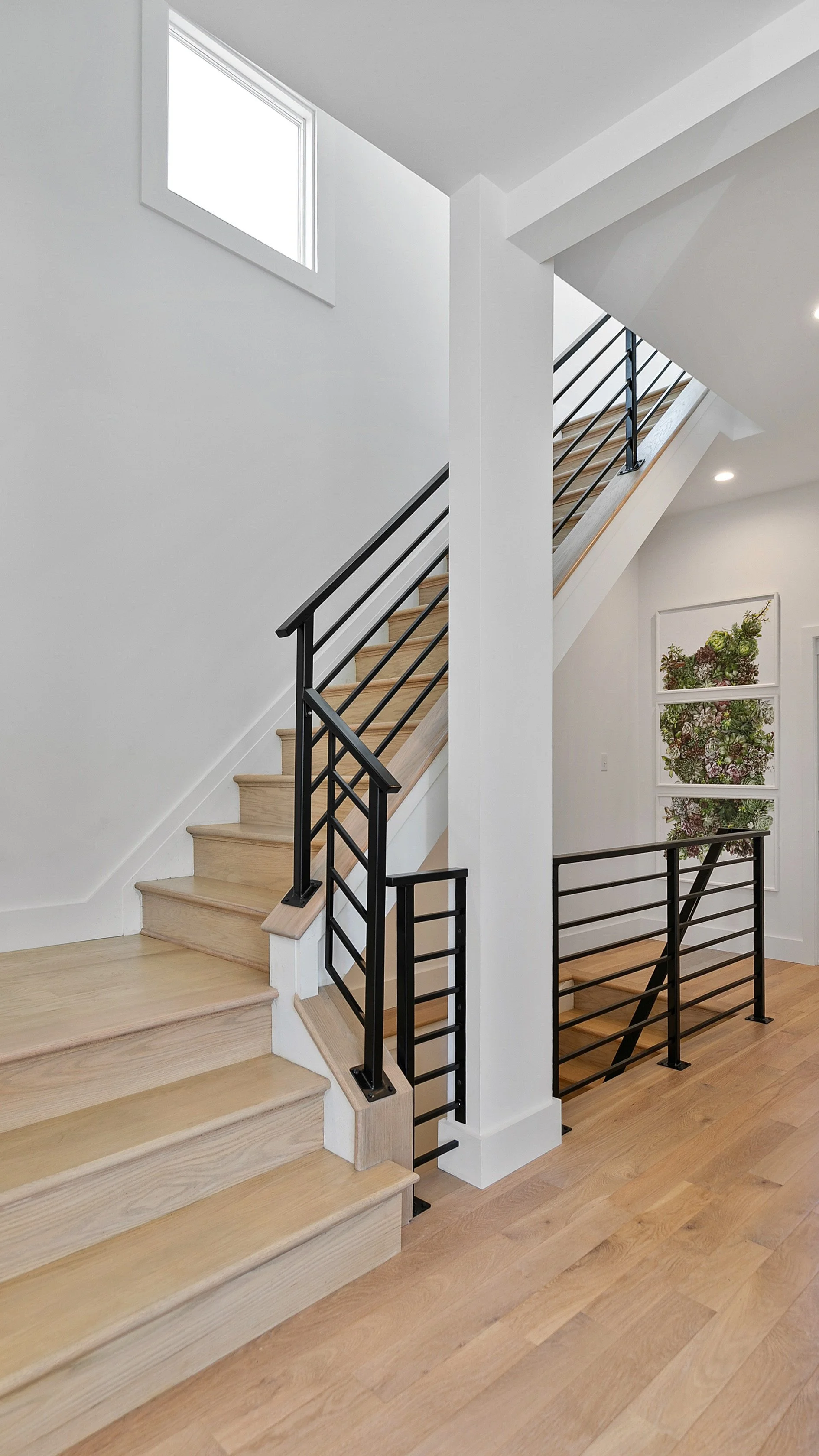 Modern staircase with black metal railings and light hardwood stairs professionally staged at 2 N Brunswick St Richmond VA
