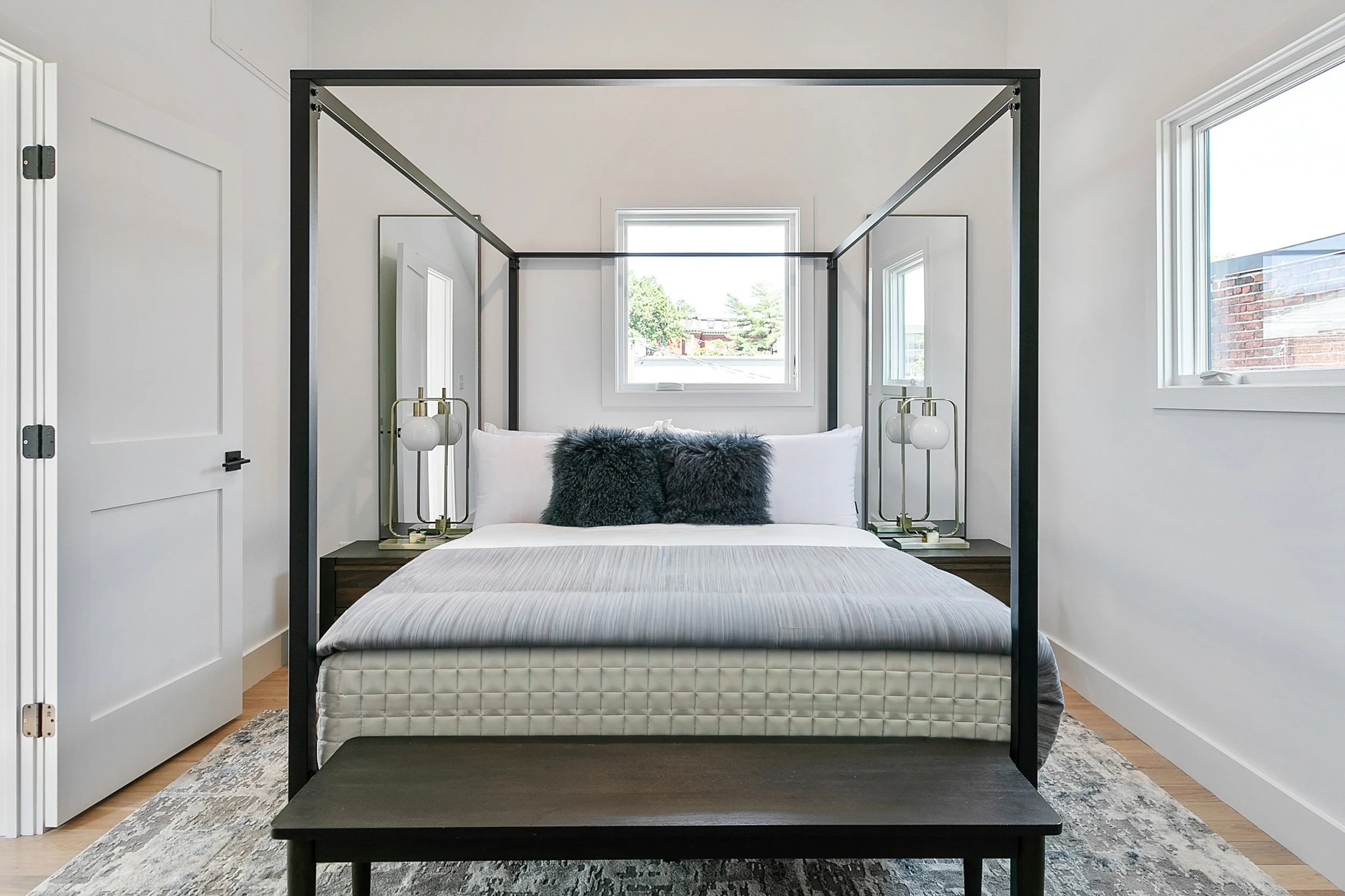Luxury master bedroom after professional home staging at 2 N Brunswick St Richmond VA featuring four poster bed, navy and white pillows, and modern organic design by Jsquared RVA