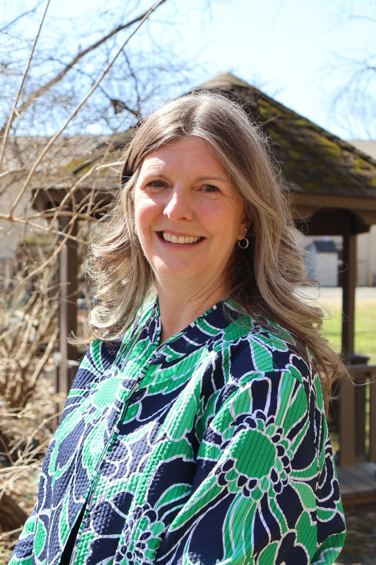 Lynette smiling, standing in nature