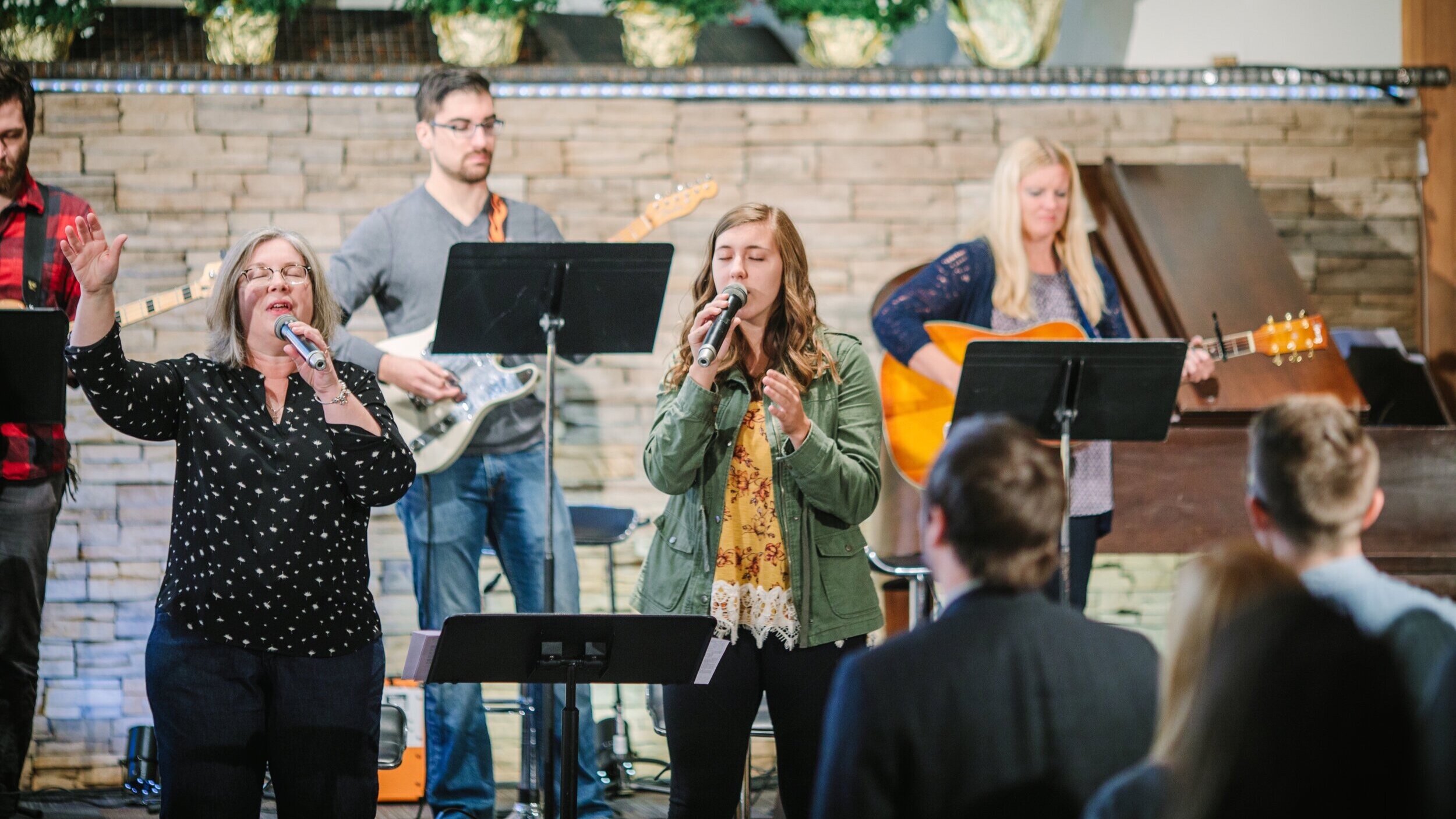 Image of men and women singing, playing guitar, and worshiping