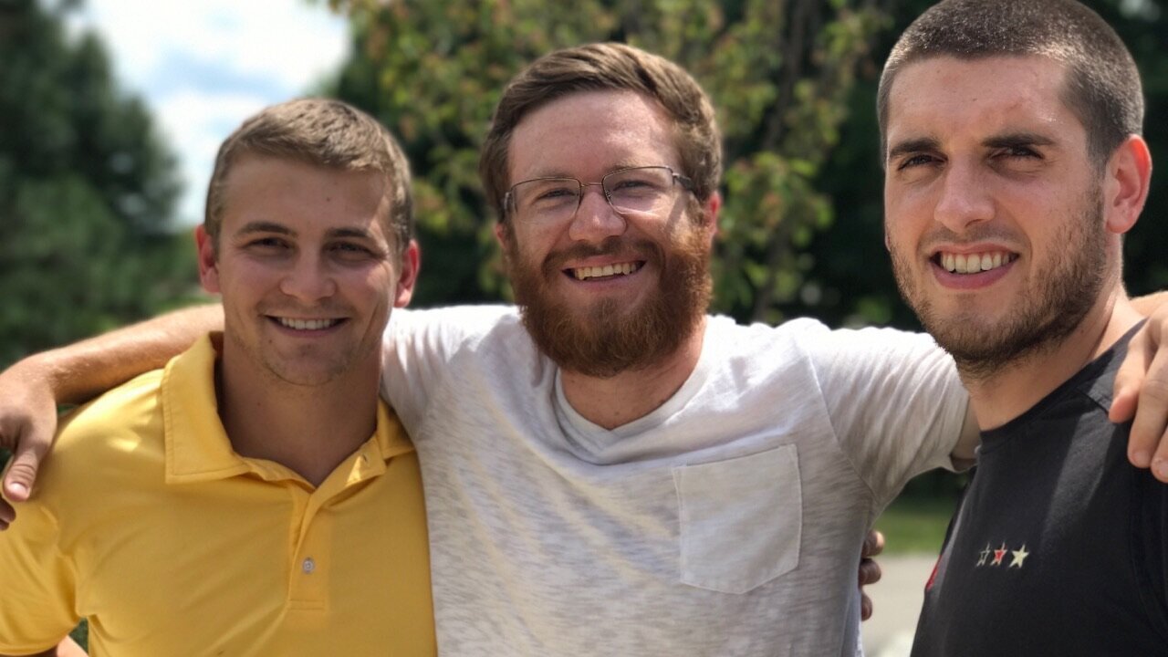 3 men smiling with their arms around each other
