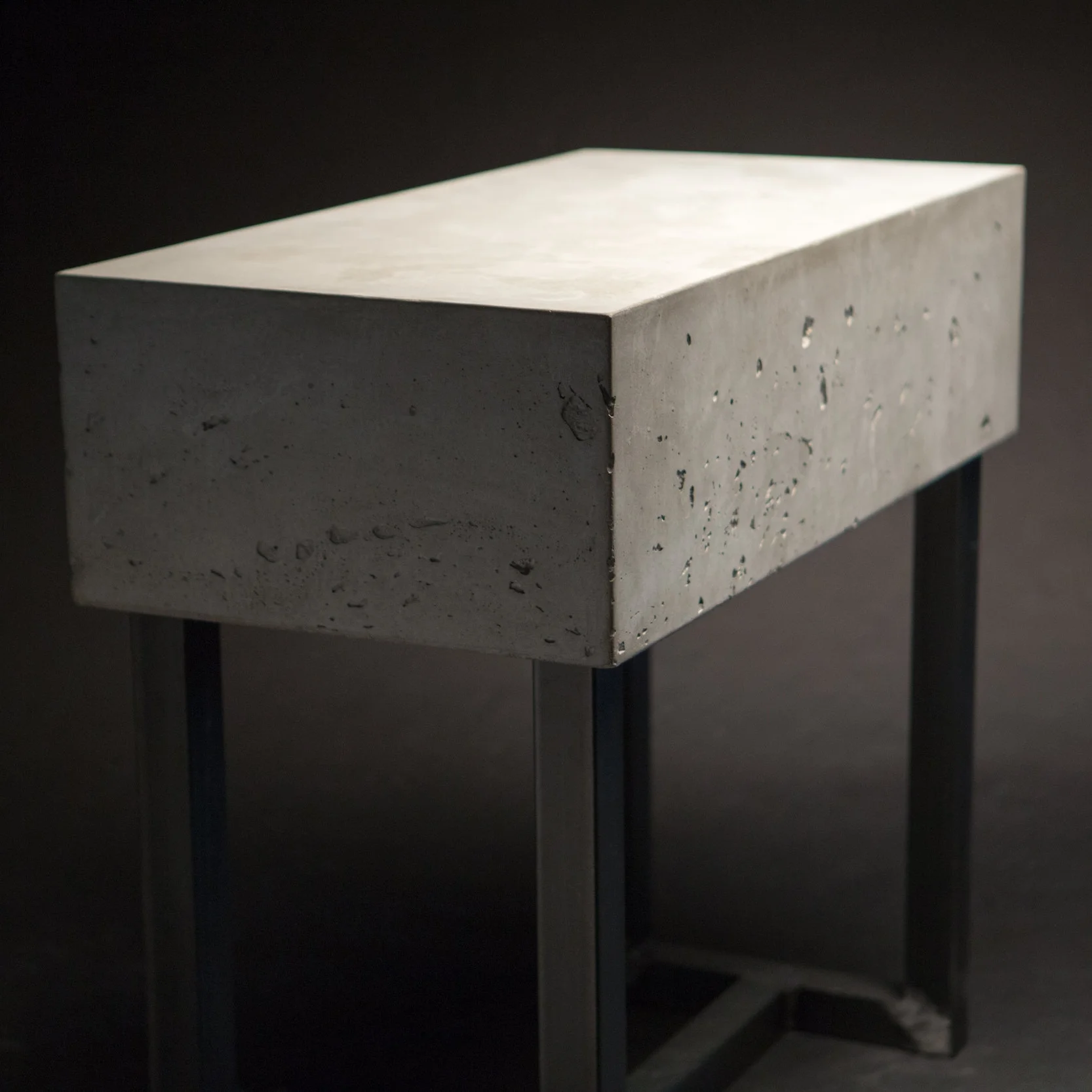a table with a very thick gray concrete top and a raw welded steel base