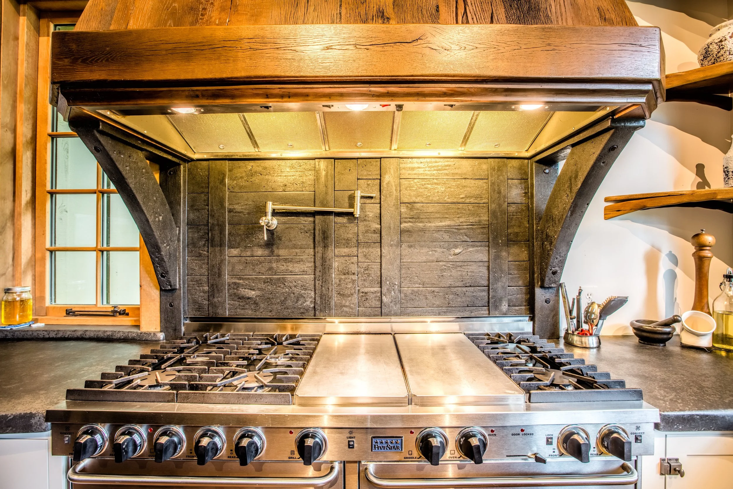 A concrete backsplash and hood support cast to look like recovered barn wood. The perfect functional and aesthetic solution because of fire hazard over a gas range. #residential