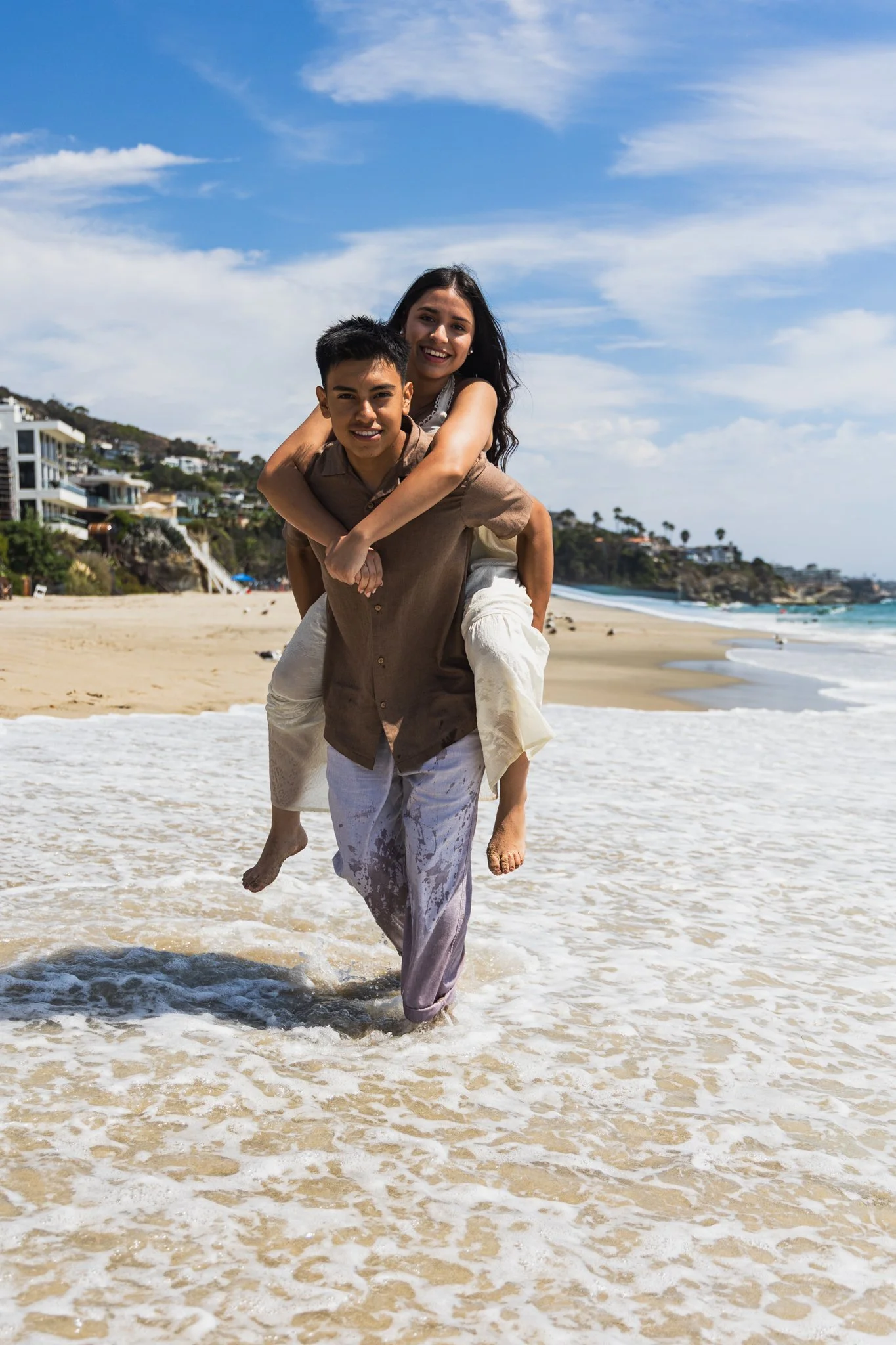 Eduardo carries Emily on his back walking the beach