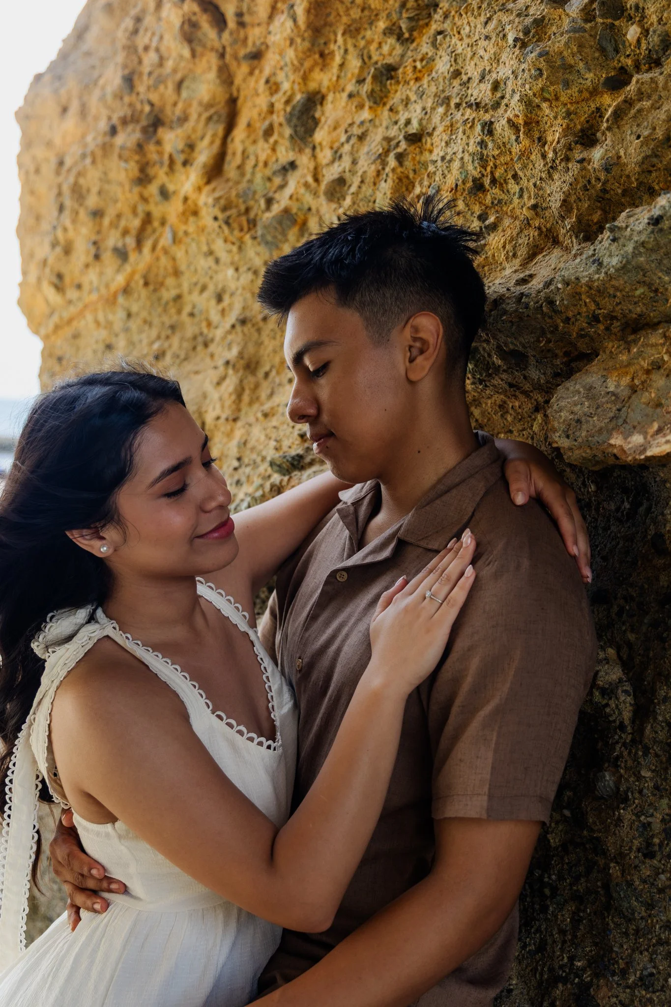 Emily leans on Eduardo against a rock