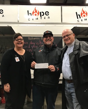 Fr. Victor presenting the check to Larry and Stephanie of the Hope Center.