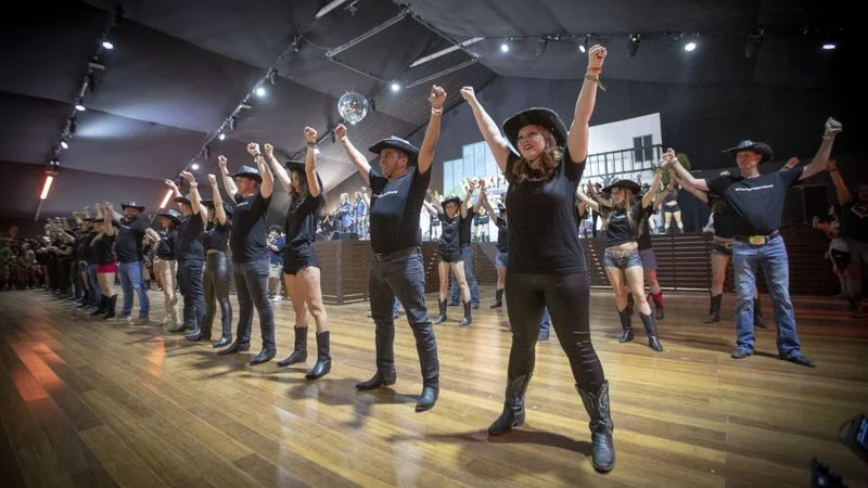 LA WRANGLERS RAISE THEIR HANDS IN UNITY AFTER PERFORMING A COMMEMORATIVE LINE DANCE SET TO COUNTRY STRONG: A SONG WRITTEN ESPECIALLY FOR THE OCCASION BY HONEY COUNTY foreground from right to left: LA Wranglers Lindsey Castillo, Mark Nunez, Katya Jenini-Hutson, Luke Bowerman, Christina Ramos and Rick Dominguez Photo credit: Allen J. Schaben of the Los Angeles Times Song: Country Strong by Honey County Choreography: Annemarie Dunn and Kristal Lynn Konzen