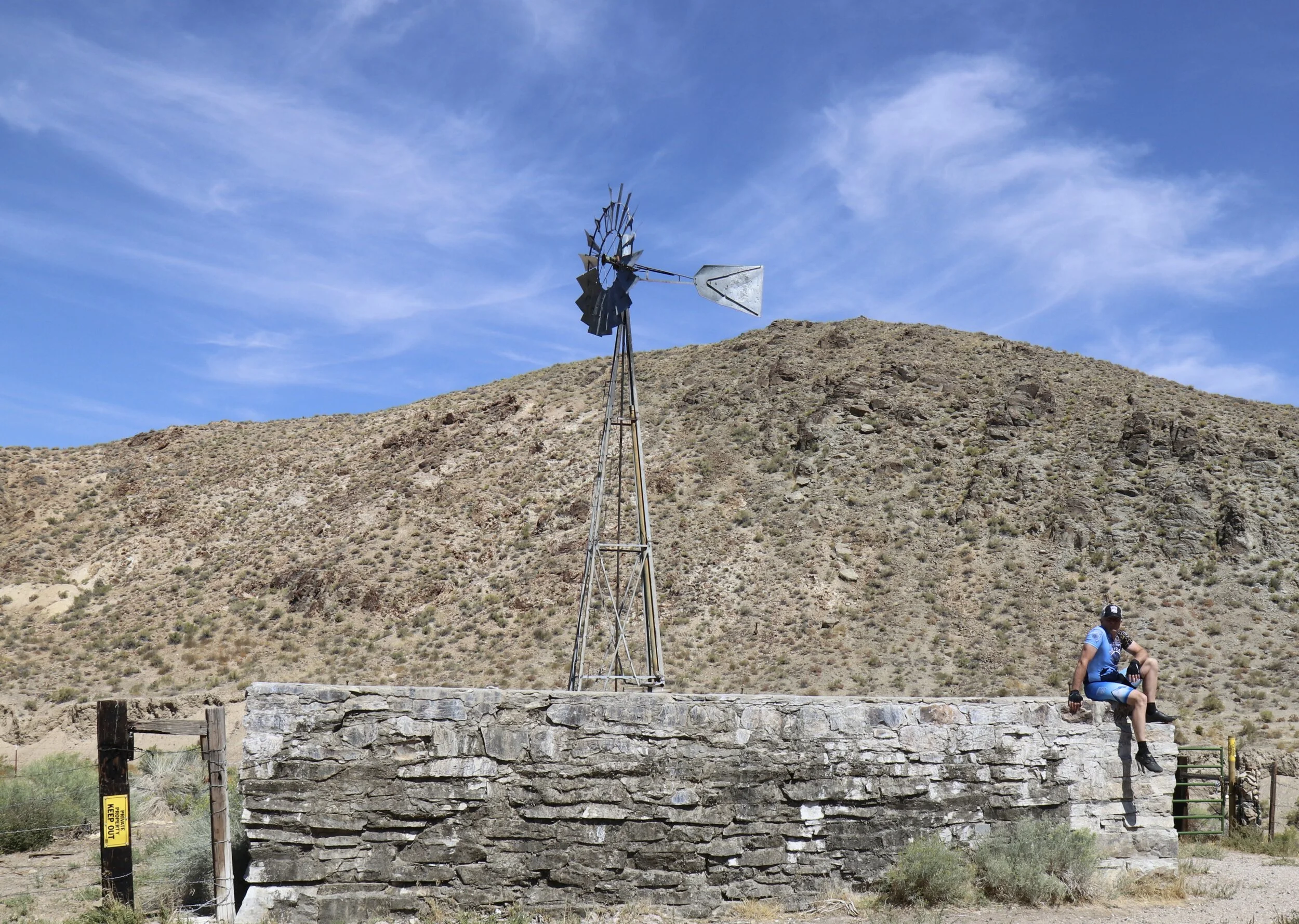 Me sitting on the edge of a huge water retention basin filled by the windmill on the Pony Express Route across Nevada.