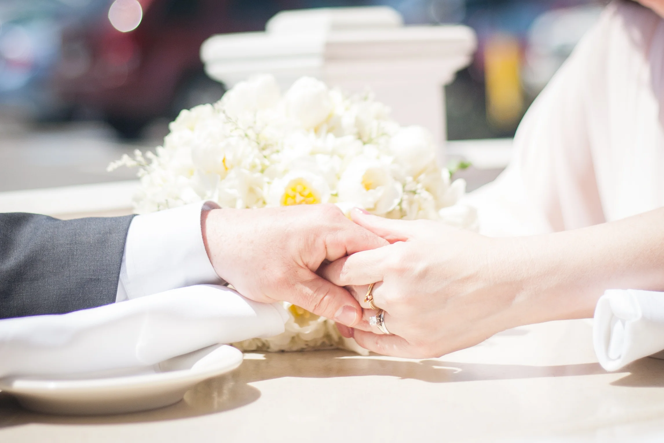 Close-up of hands holding a bouquet of white flowers during a wedding ceremony.