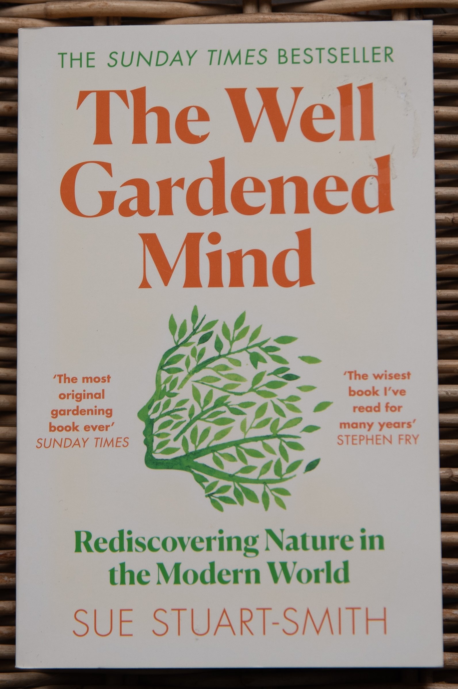 Book cover of The Well Gardened Mind by Sue Stuart-Smith, with an illustration of a human profile formed from green leaves and branches.