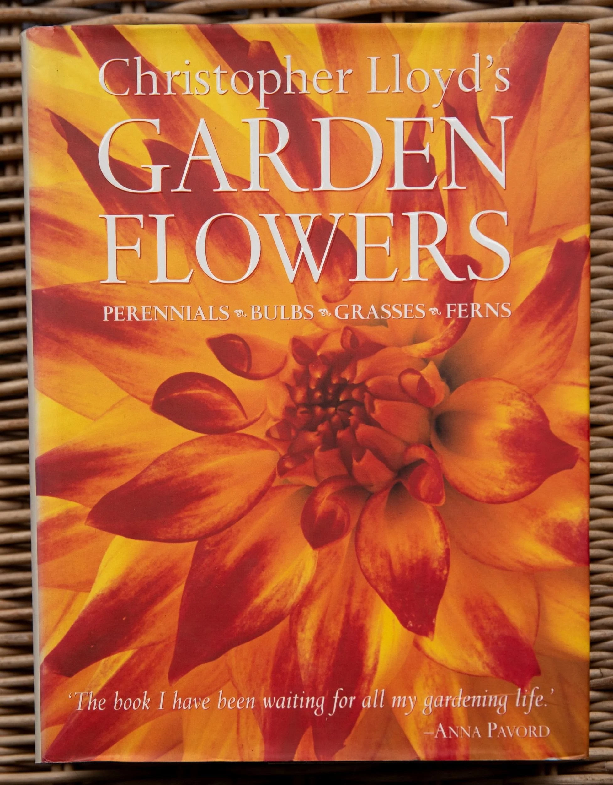 Book cover of Christopher Lloyd's Garden Flowers, featuring a close-up photograph of a vivid orange dahlia in full bloom.