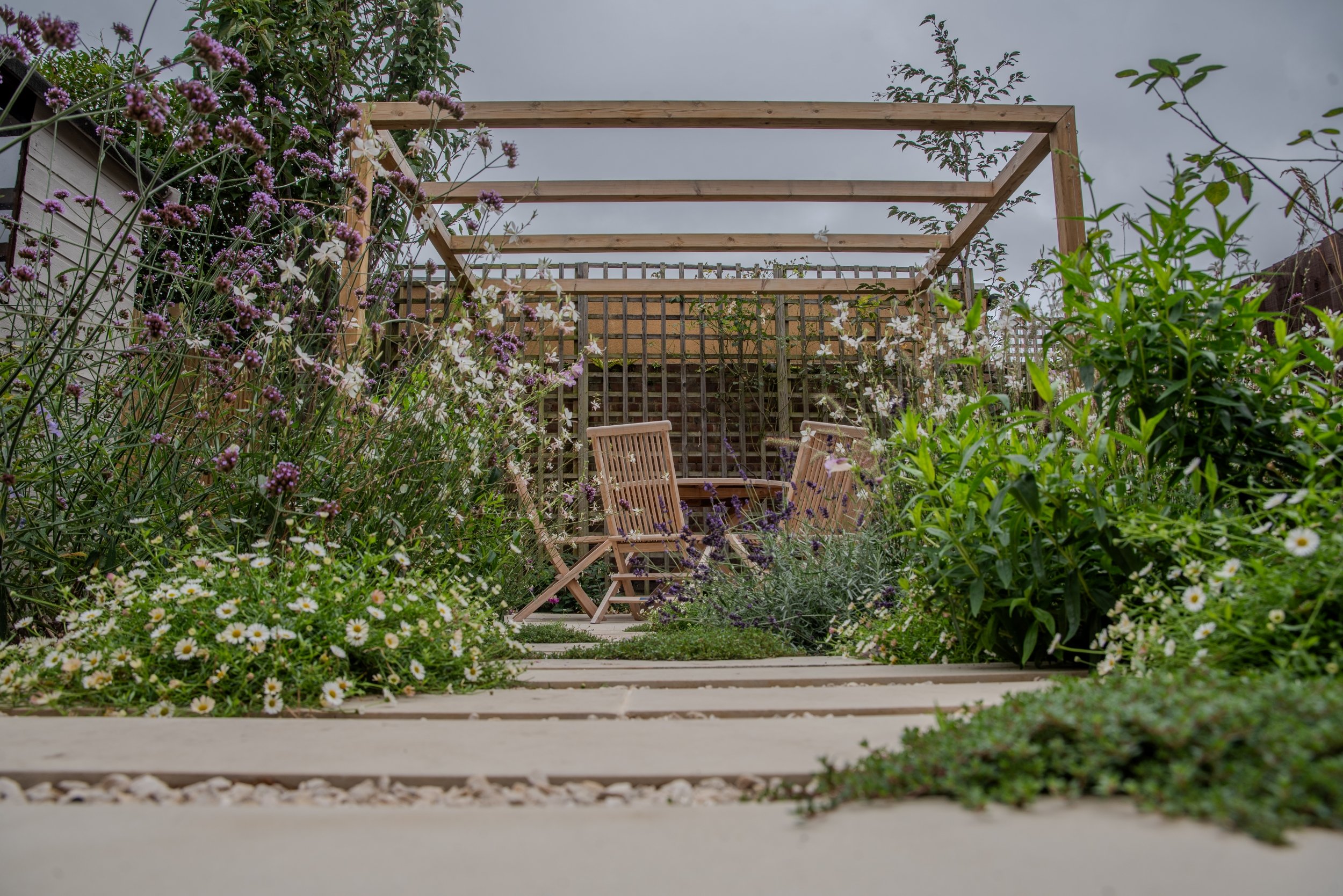 Timber pergola and seating area glimpsed through cottage garden planting, Wandsworth garden by Jane Shankster Garden Design

A timber pergola frames a cosy seating area at the end of the garden, glimpsed through a rich tapestry of verbena, gaura and 