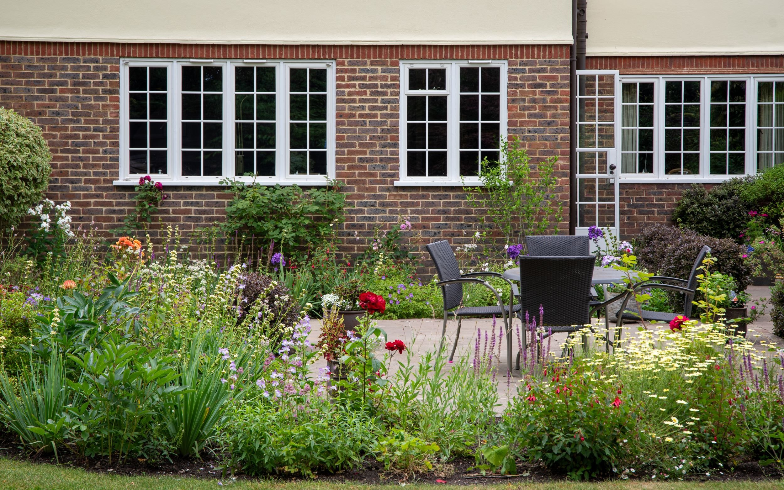 Colourful mixed border along house facade, Surrey replanting by Jane Shankster Garden Design

A vibrant mixed border runs the length of the house, combining salvias, achillea, penstemon and fuchsia in front of mature brickwork and white-framed window
