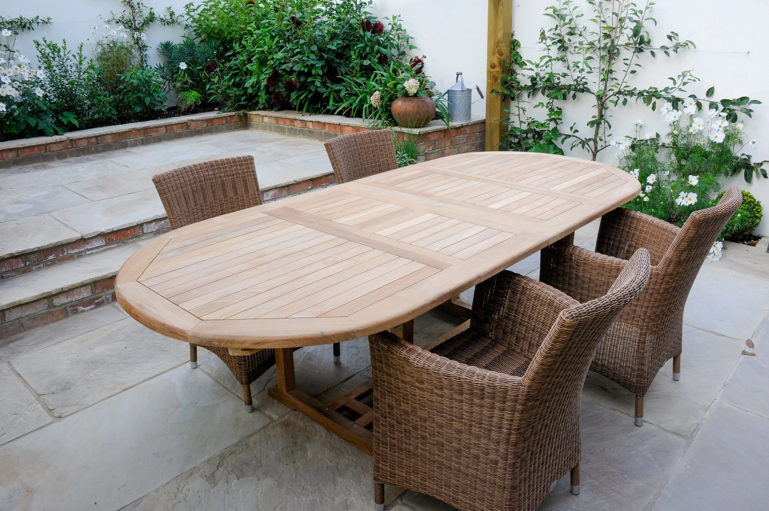 An oval teak dining table with six wicker chairs on sandstone paving in a courtyard garden

An oval teak table seats six wicker armchairs on honed sandstone paving, positioned to make the most of the Balham courtyard garden for outdoor dining and ent