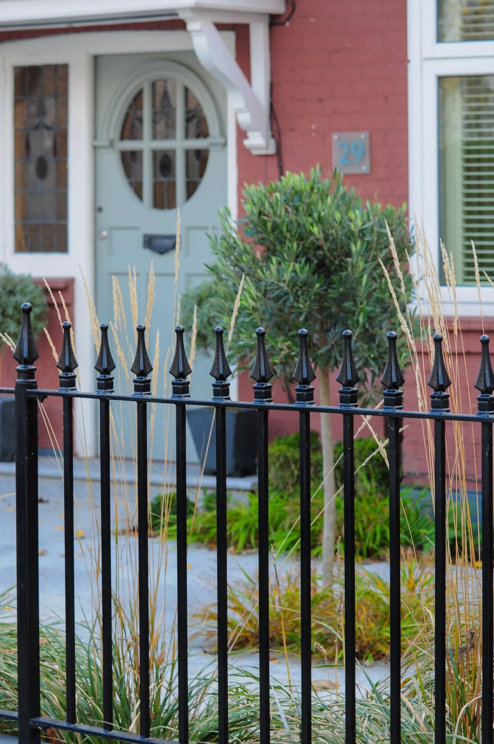 Black railings with ornamental grasses framing front door, Twickenham garden by Jane Shankster Garden Design

New black railings topped with ornamental grasses frame a view towards the front door, with a neatly clipped olive tree standing sentinel be