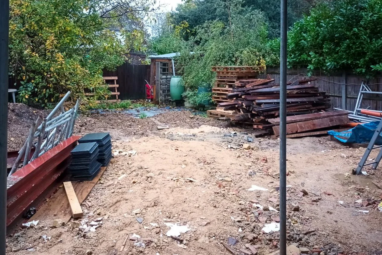 Overgrown garden site before landscaping, property development

The garden prior to landscaping, showing a cleared building plot with stacked timber, scaffolding materials, and construction debris awaiting removal. This before shot illustrates the sc