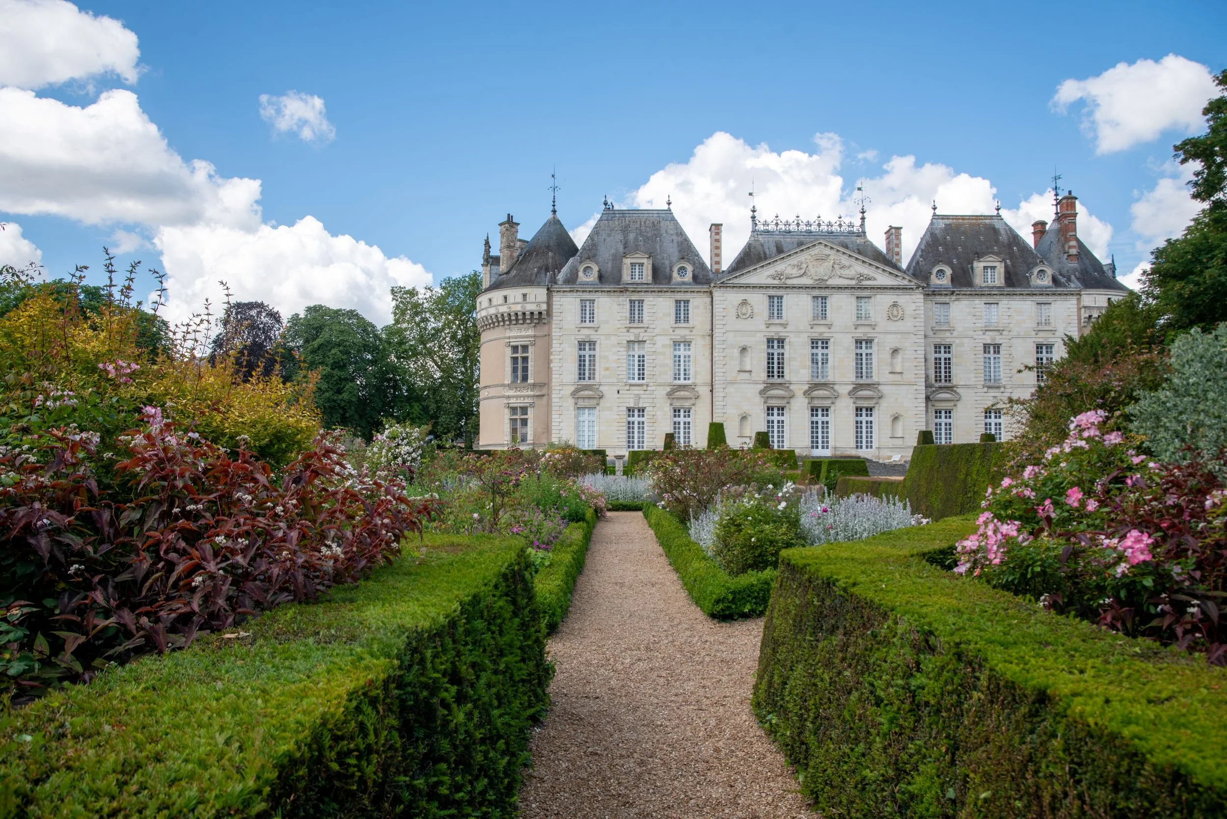Box-edged rose garden path at Château du Lude leading towards the château's elegant white stone facade.